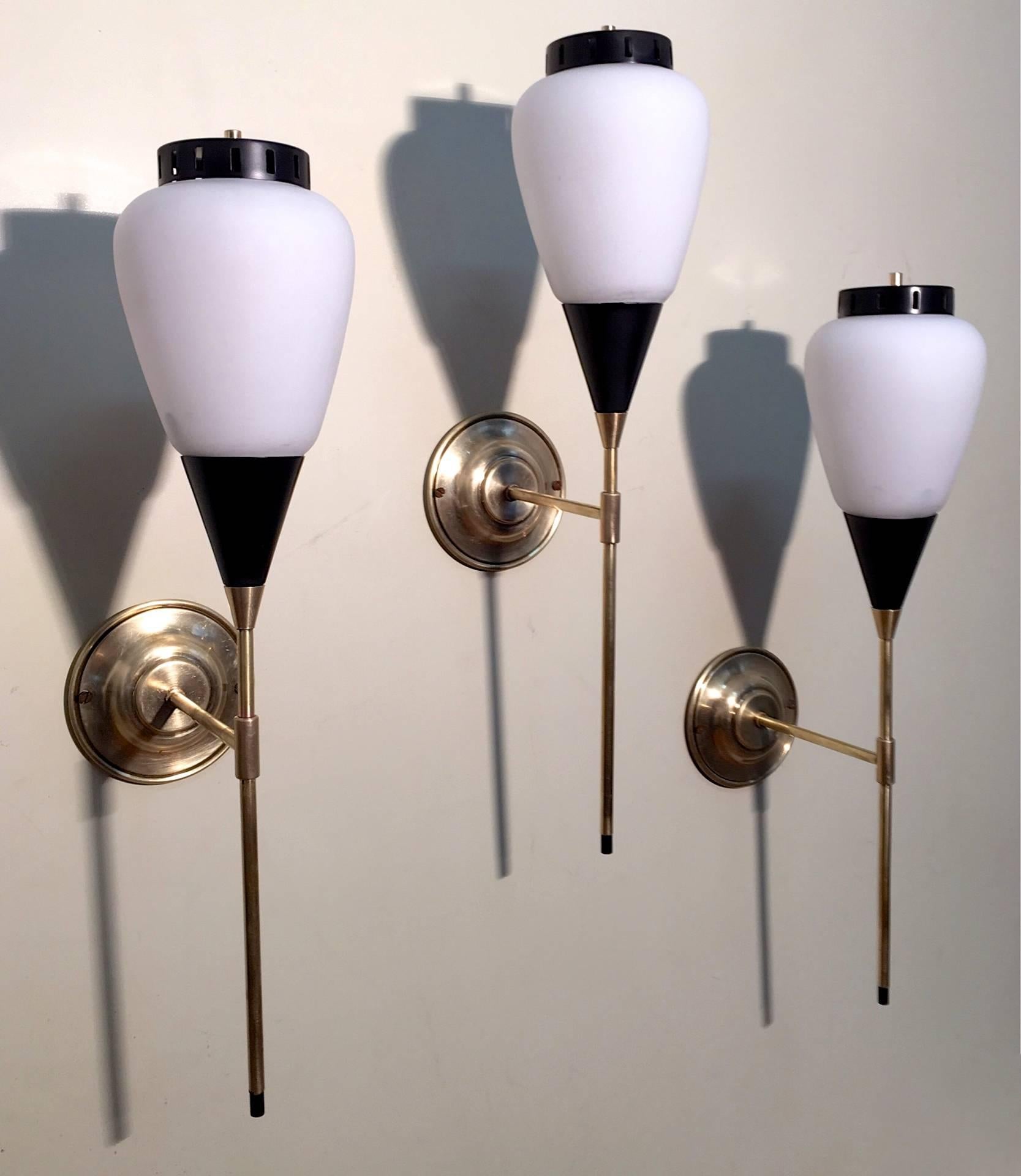 A set of three Classic Italian modern wall sconces with modernist features.
Opaline glass shades and black metal details, brass attachments, circa 1950.

 