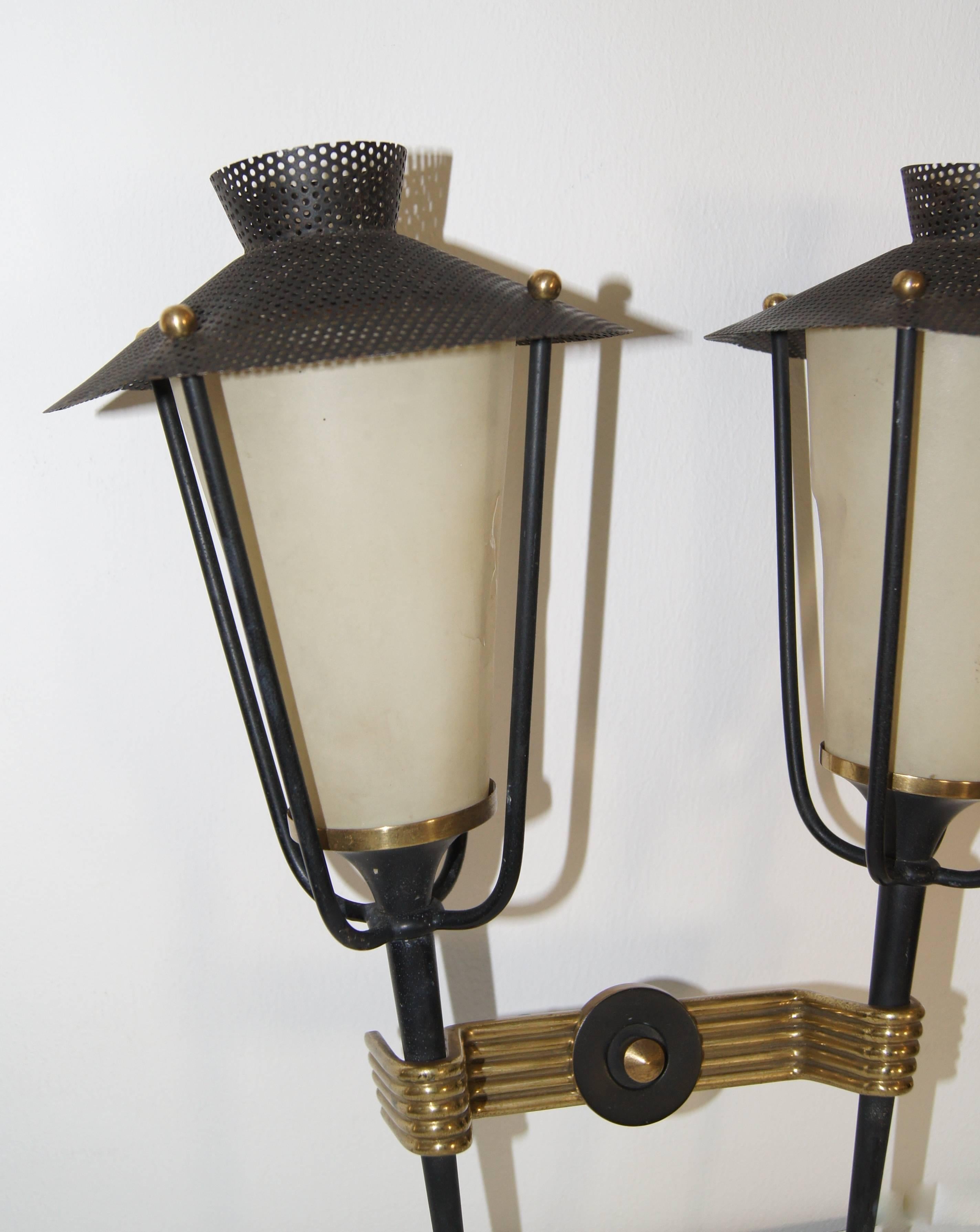 Two lanterns tied together by a brass middle section. Black perforated steel canopies that diffuse the light. The shades are original. A light rapture is visible.
They are a type of cellulose film first made in France in the 1930s.