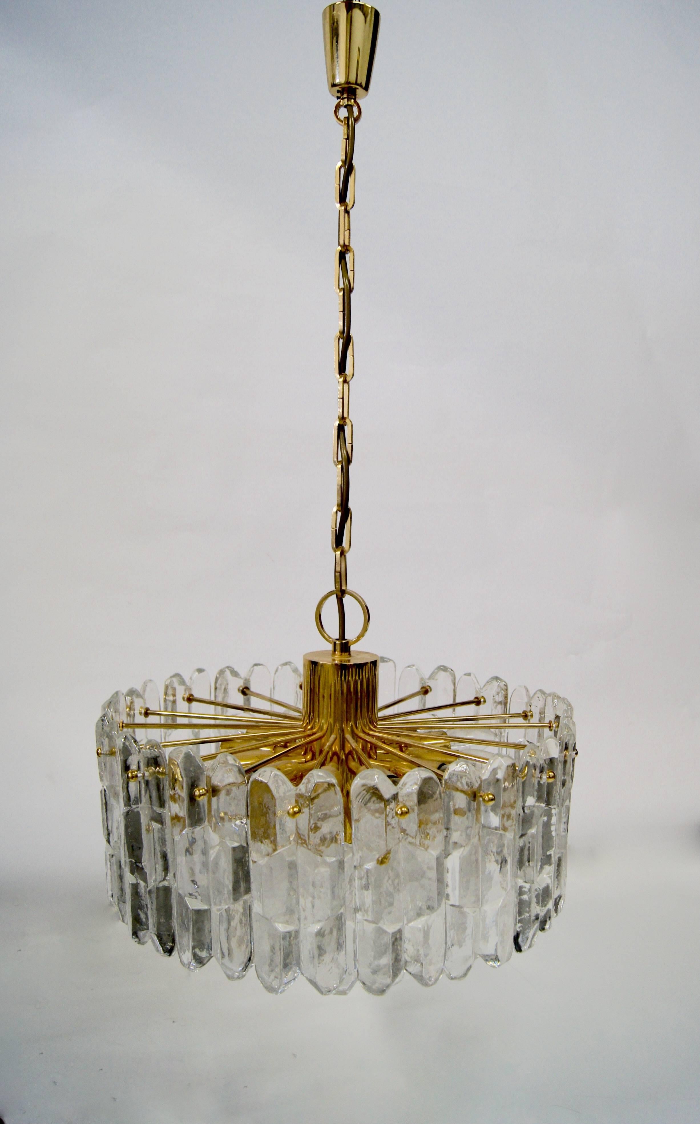 This Articulate chandelier named Palazzo is decorated with thick ‘ice glass’ cut crystals on a 24-carat gold plated brass frame. Twelve small base bulbs are neatly arranged on the top of the pendant and one in the centre at the bottom of this triple