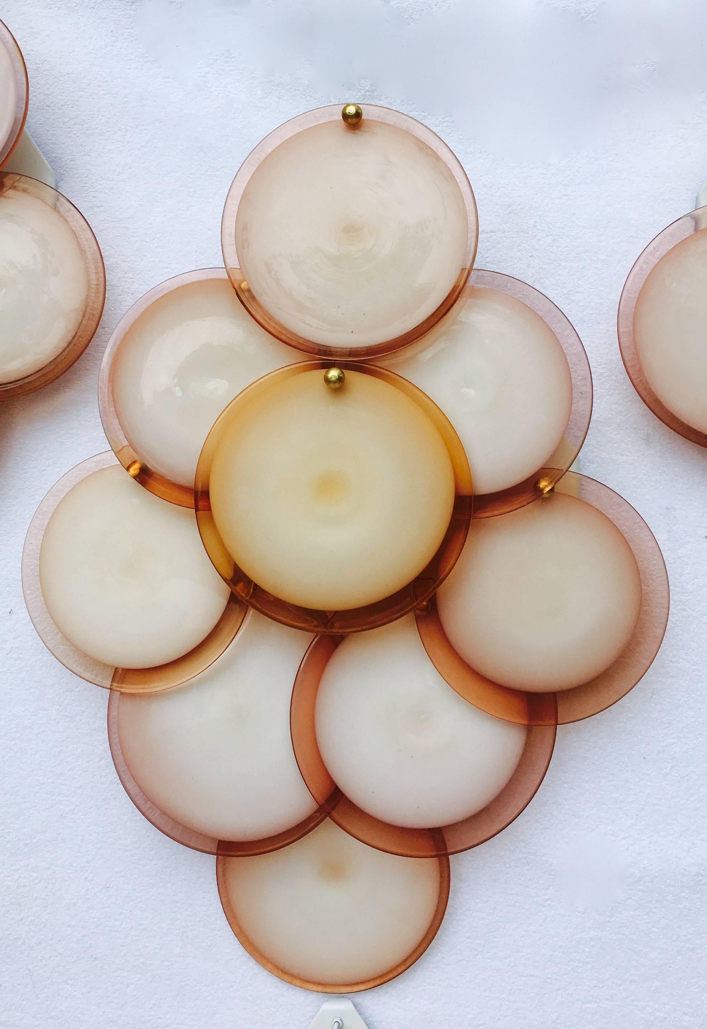 This set of large wall lights has nine overlapping rose opaque discs with smoked topaz perimeters mounted on a metal back panel with brass rods. Each disc has been handblown in Venice. The fixtures accommodate two bulbs each and are in great working