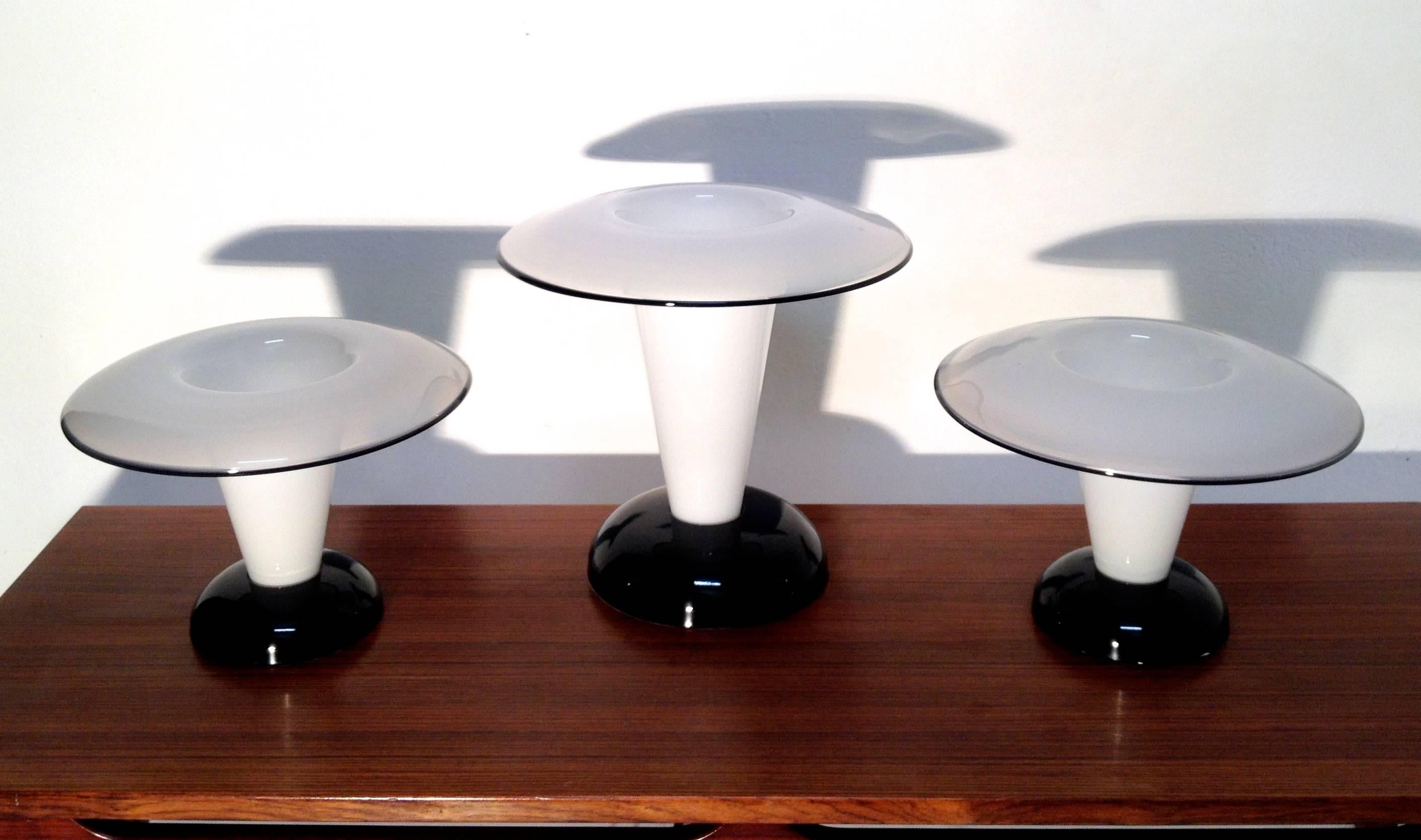 Set of three wonderful Italian Murano glass mushroom lamps with opaline glass and black rim. The base is of black lacquered metal and gives the design a very authentic signature. The top is opened and holds a regular fitted bulb. 