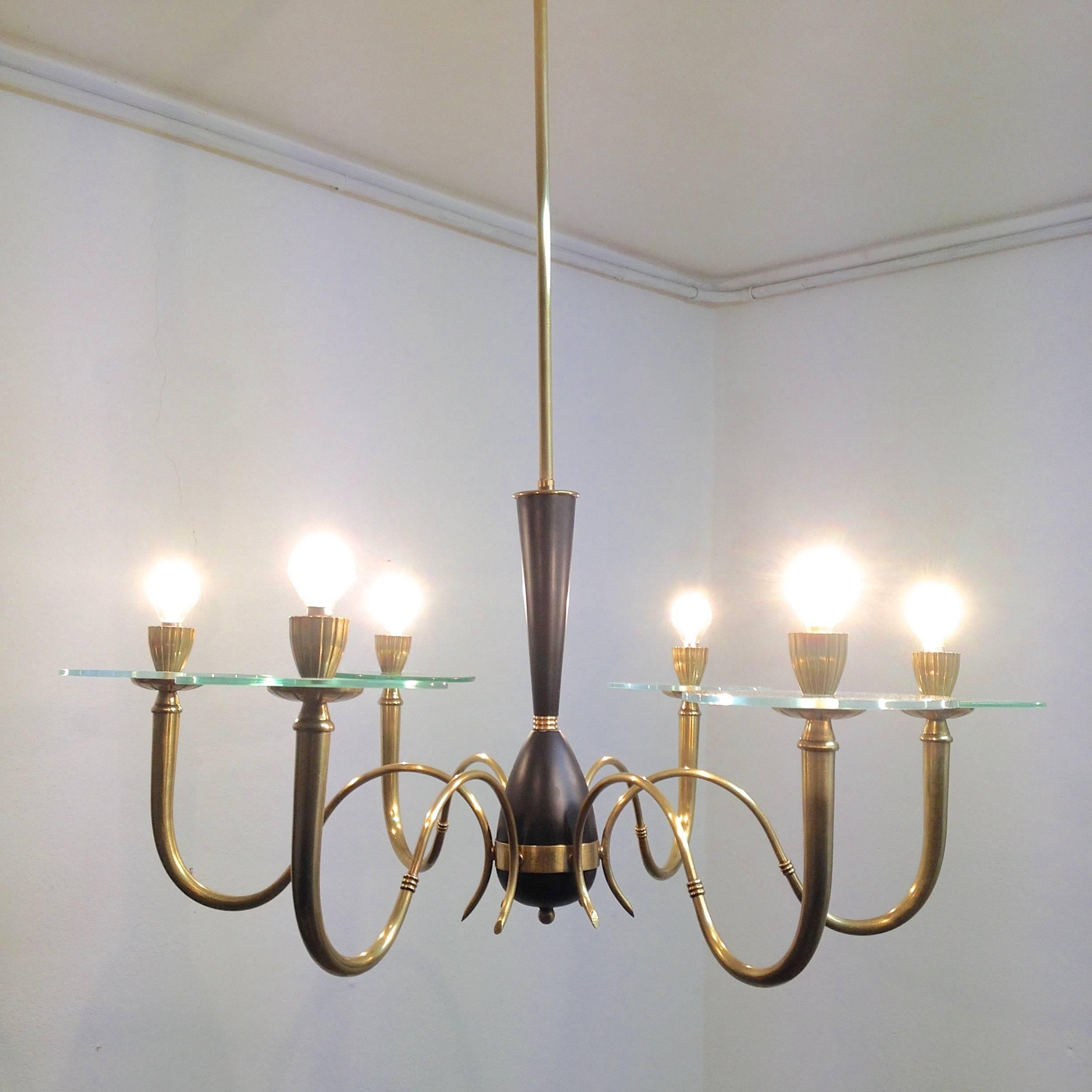 Elegant but modern chandelier with 6 brass arms that hold a glass disc, 3 with a green nuance and 3 more clear coloured glasses. Middle section is black metal and brass details. The sconce of the light fittings are rimmed and have nice detail
