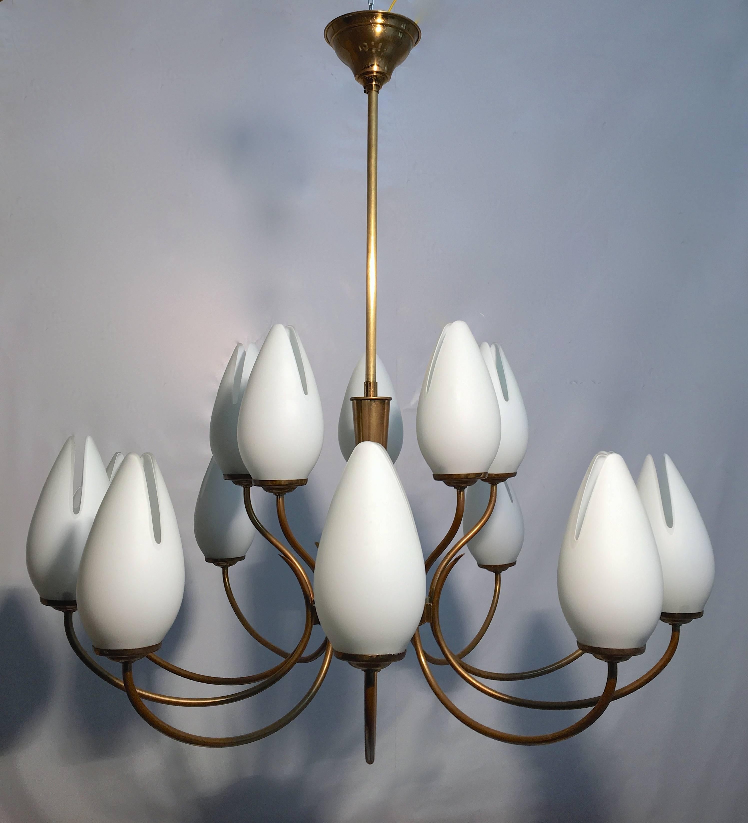 Very decorative brass chandelier with double cased opaline Murano glass shades that resemble a tulip shape. Neatly divided in three tiers the lamp has a beautiful resemblance to a flower as a whole.
 