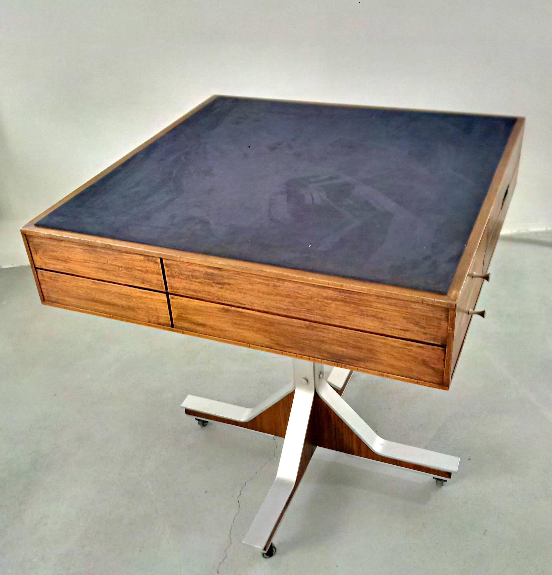 Game table with drawers and small storage on two sides. Blue velvet surface and aluminium with rosewood feet that Stand on wheels.
It has lots of nice details such as the pulls on the drawers and the architectural design as a whole. It can fulfill