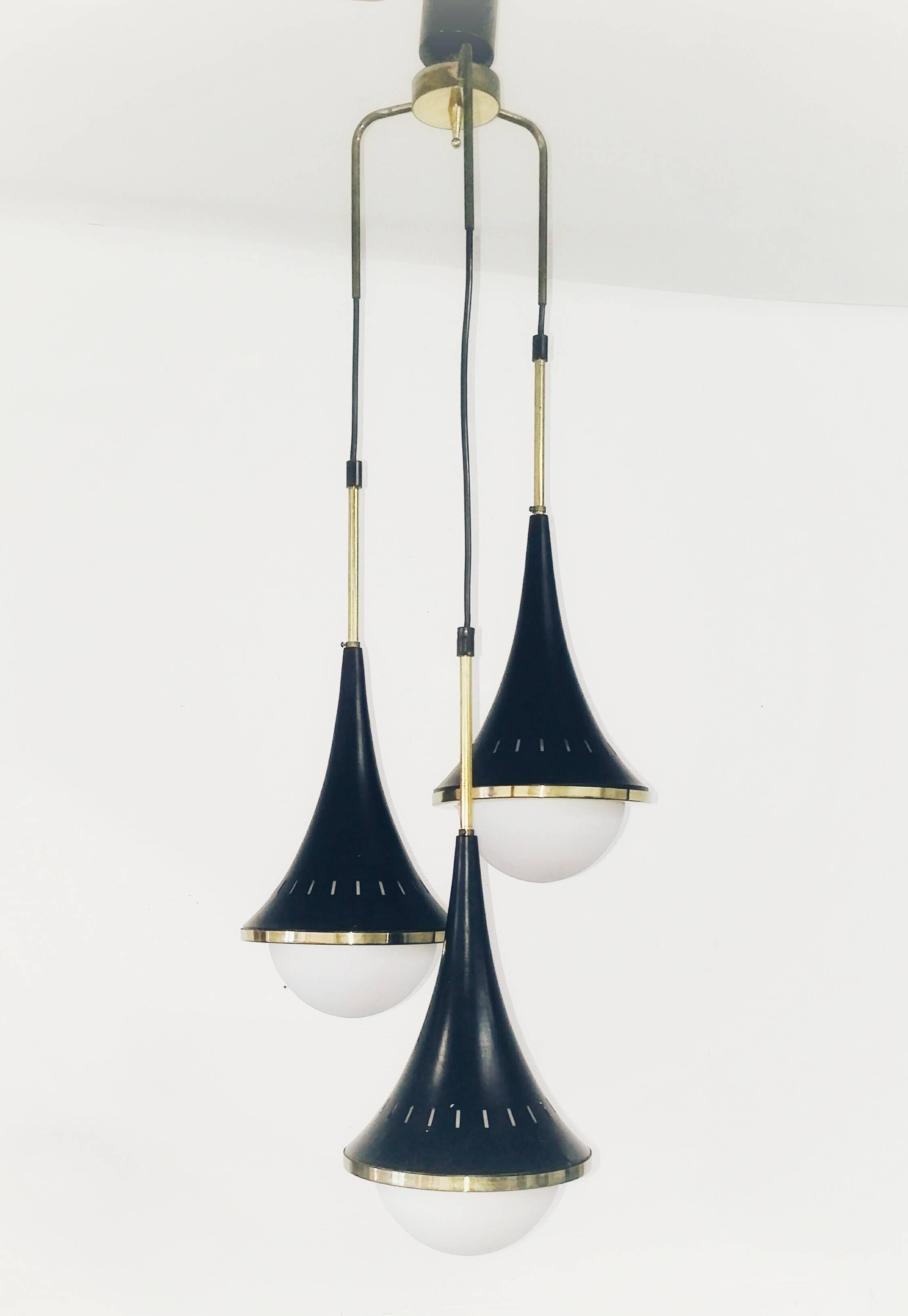 Italian pendant with three arms holding three cone shaped metal and opaline glass globe diffusers. Brass details.