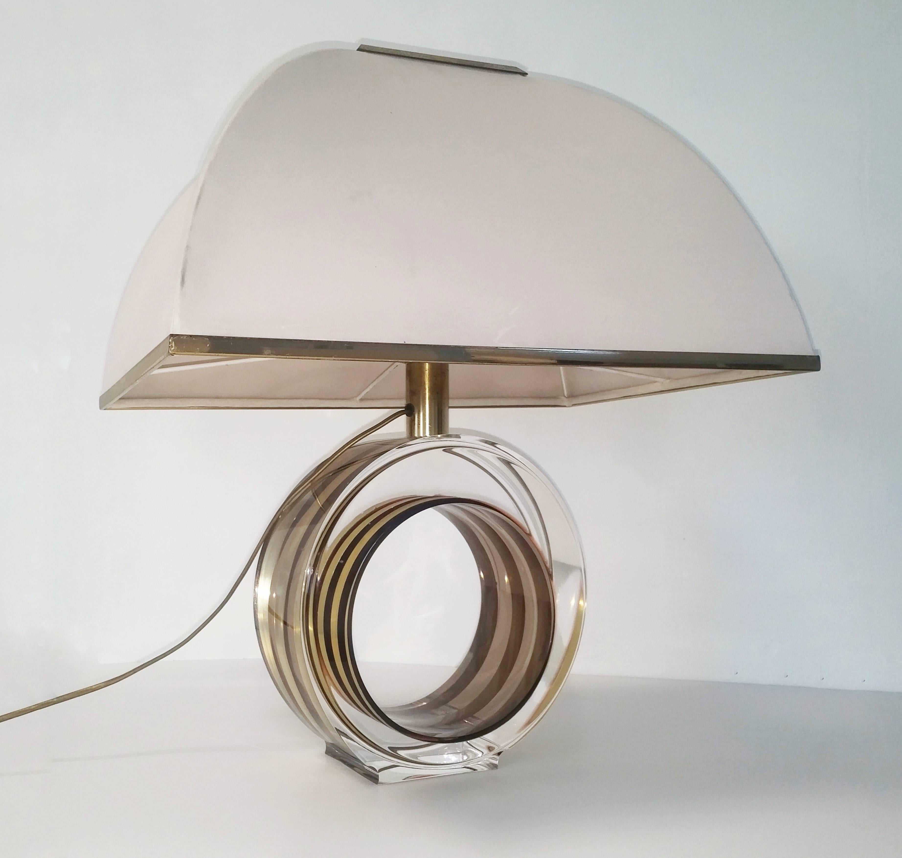 Modernist design table lamp with a brass and black metal band encased in its Lucite circular base. It has the original silk shade. Italy, circa 1970. 
Measurements in listing are including the shade.
Without shade the base measurements: Diameter