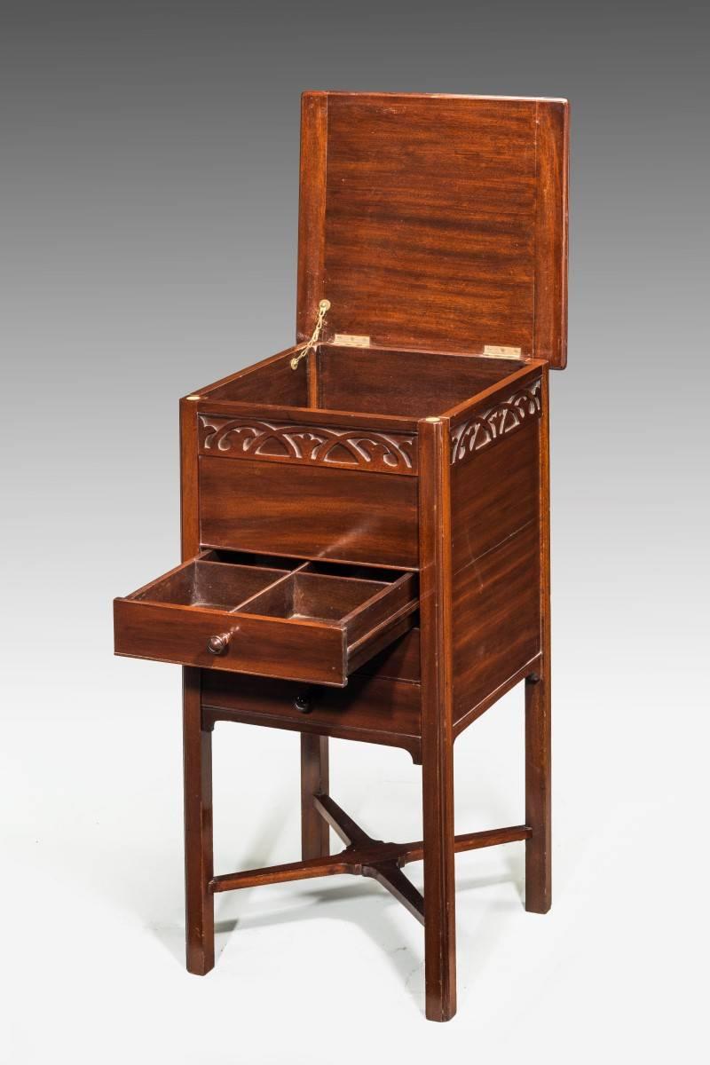 A small mahogany work table with a well carved blind fret border to the top. The lid lifting to reveal a compartment with three drawers below and original cross stretchers.