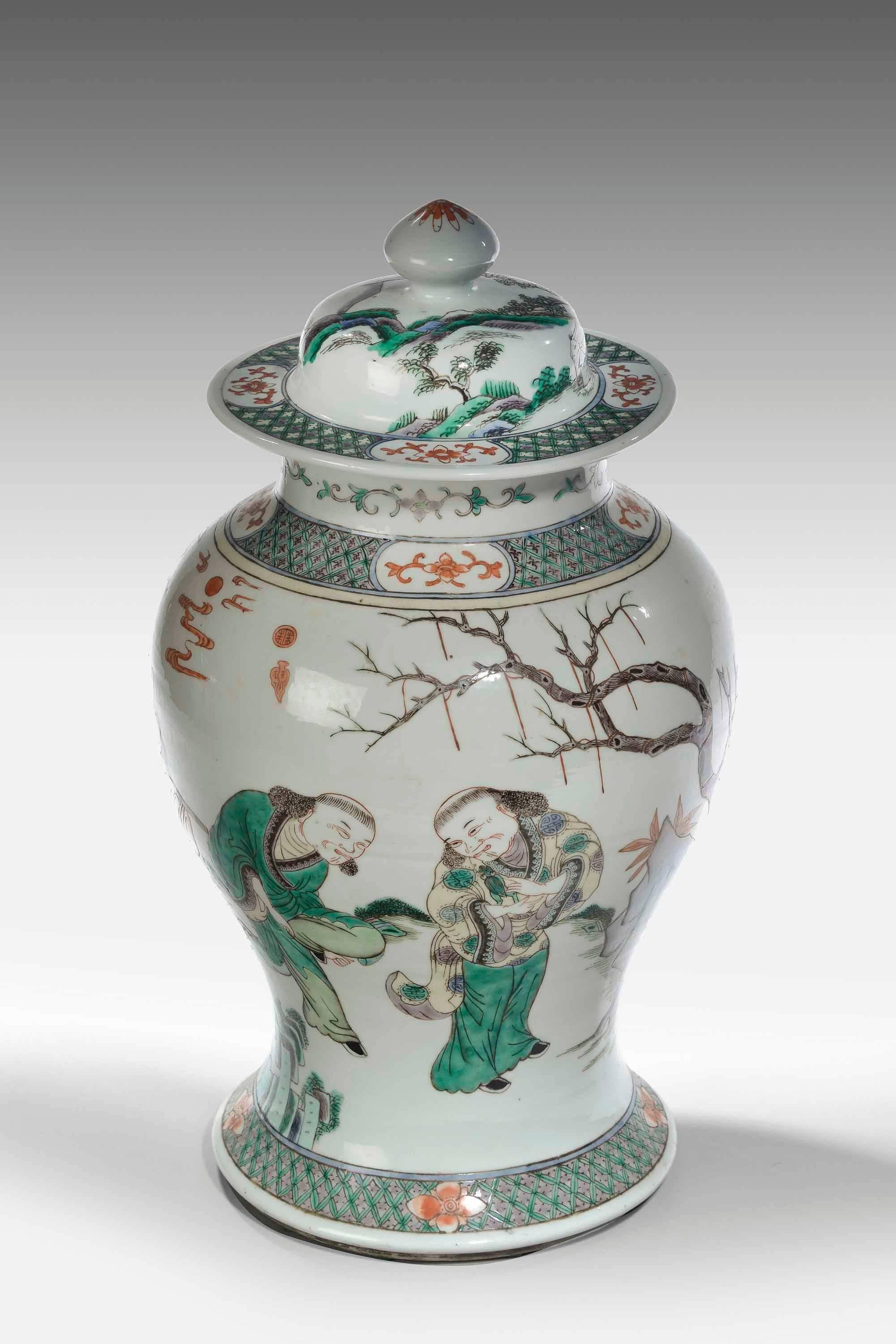 An 19th century waisted vase and lid the famille verte porcelain with exotic figures and foliage and matching borders to the top and bottom. Excellent overall condition. The domed lid carrying the same borders.