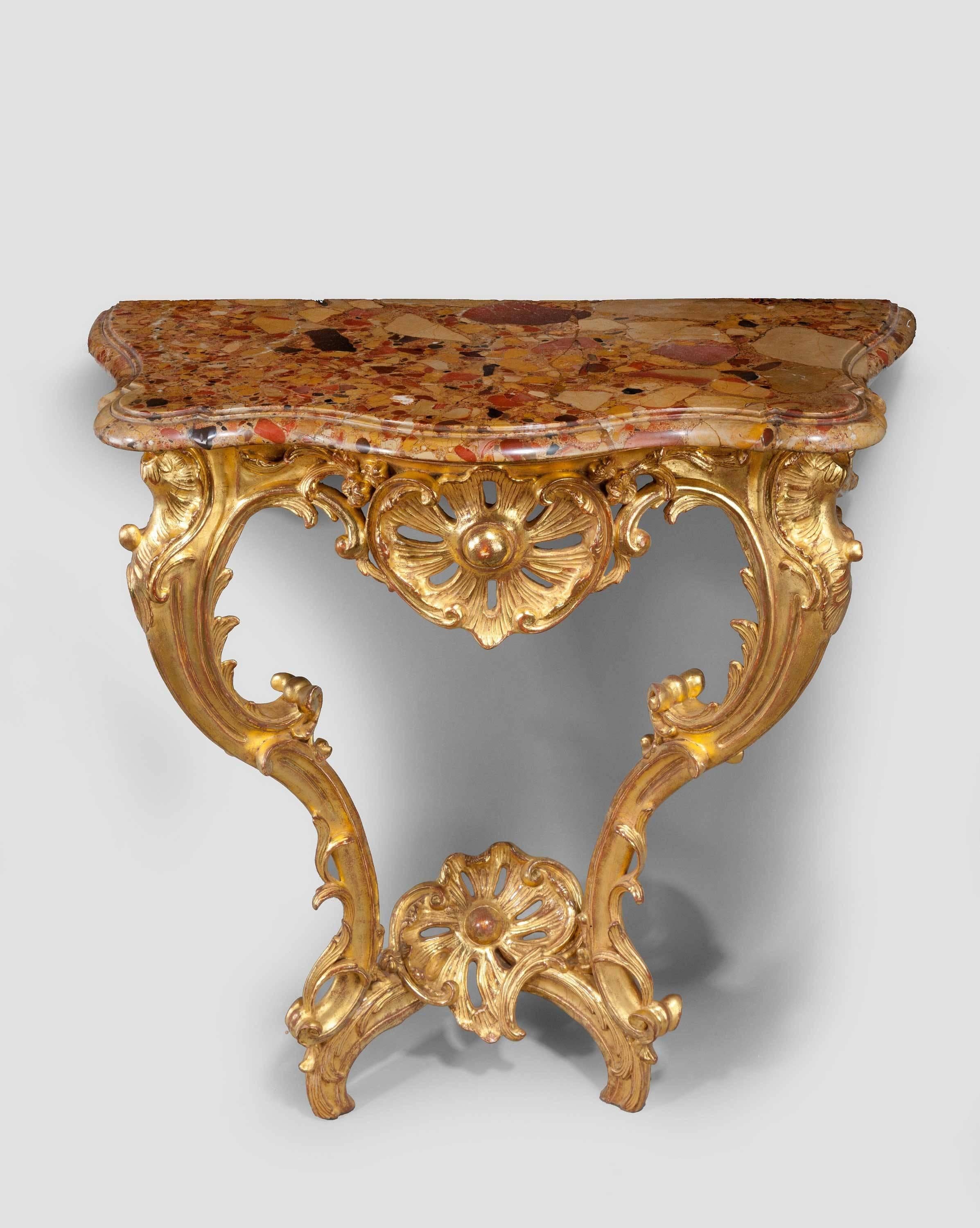 An early Louis XV Rococo giltwood console table on two elaborately carved front supports, the base with an upturned cross stretcher supporting an elaborate carved flower, well carved leaf and scroll decoration with a period marble top.
 