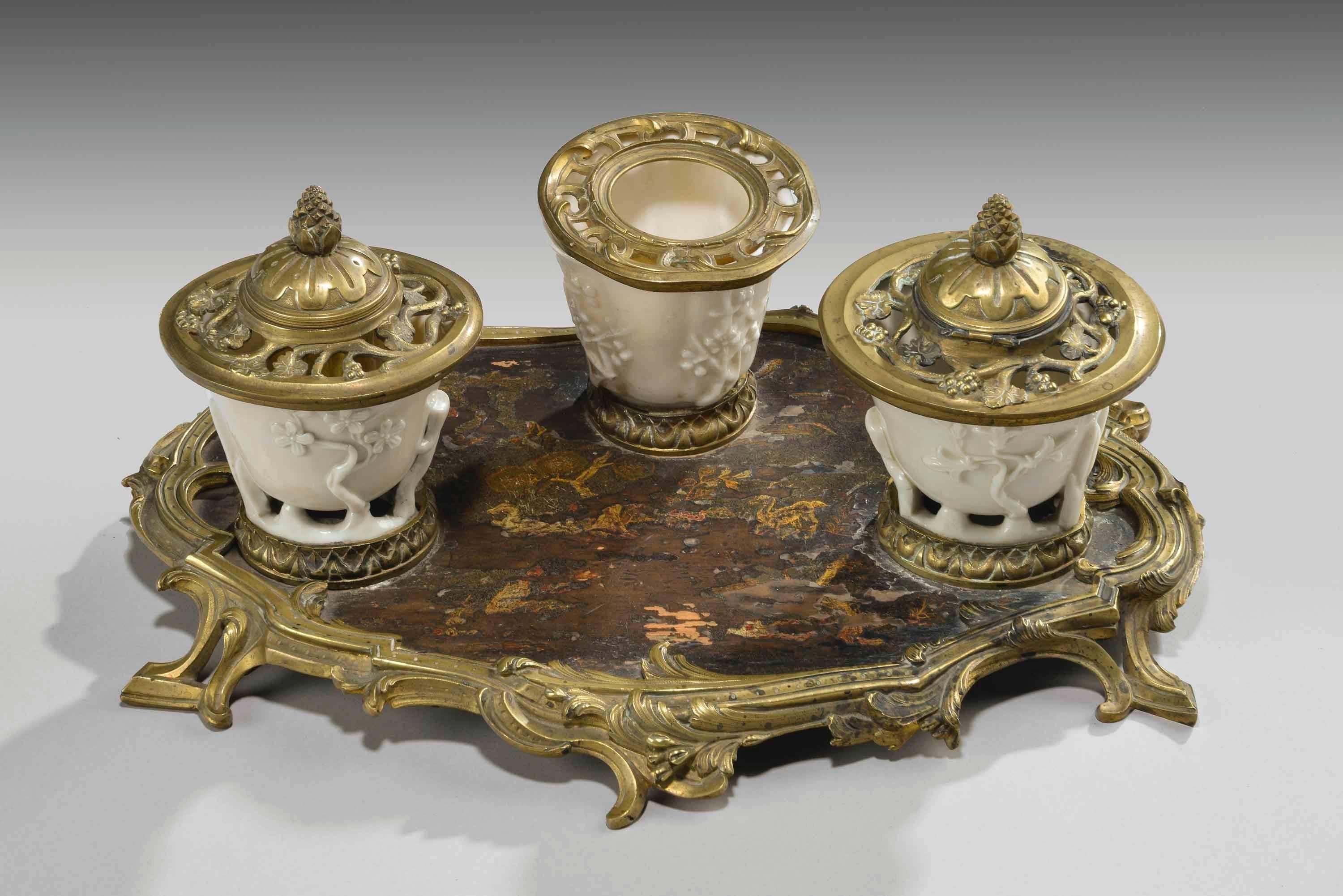 A rare 19th century gilt bronze and Chinese lacquered inkwell. The three porcelain containers of Blanc de Chine porcelain. The Rococo base framing a Chinese lacquered panel the whole in wonderful original condition.