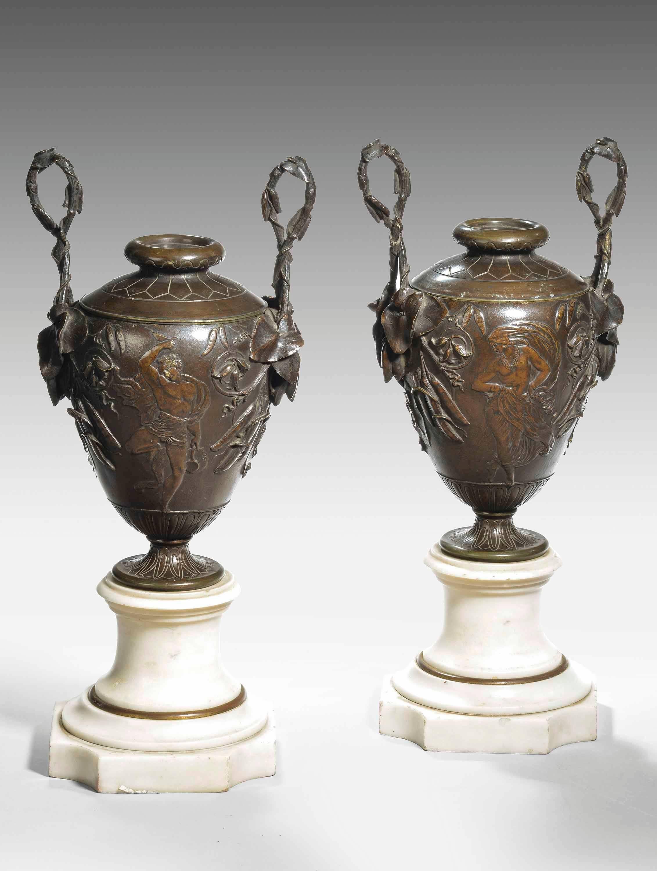 A fine pair of patinated bronze and marble urn shaped vases. The bodies with neoclassic figures and foliage. The handles with lily leaves and cementing twig tops. Reversible lids. Excellent overall condition and patina.