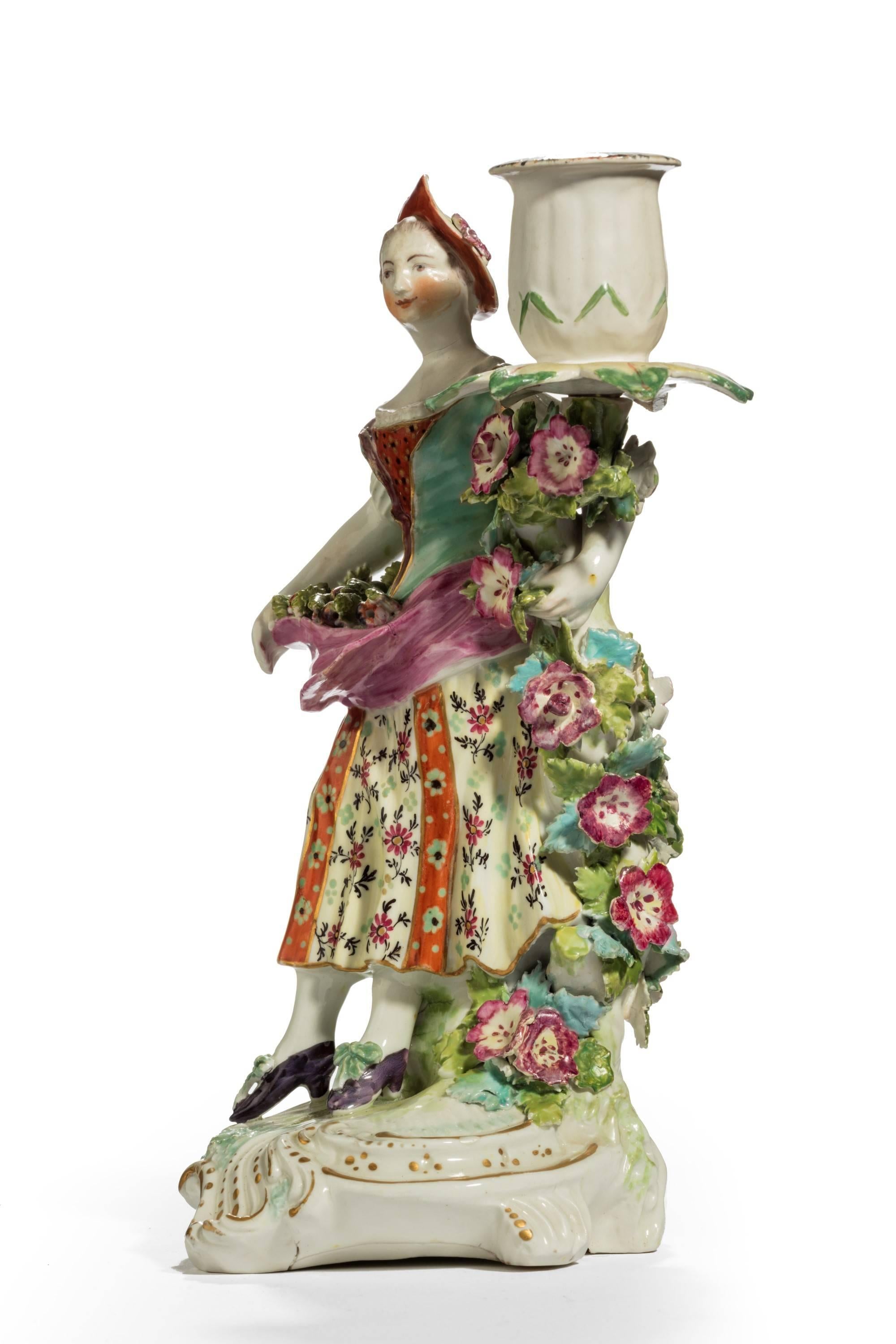 A porcelain candlestick figure of a young lady. Heavily encrusted in flowers. The base with original shrinkage marks to the underneath.
