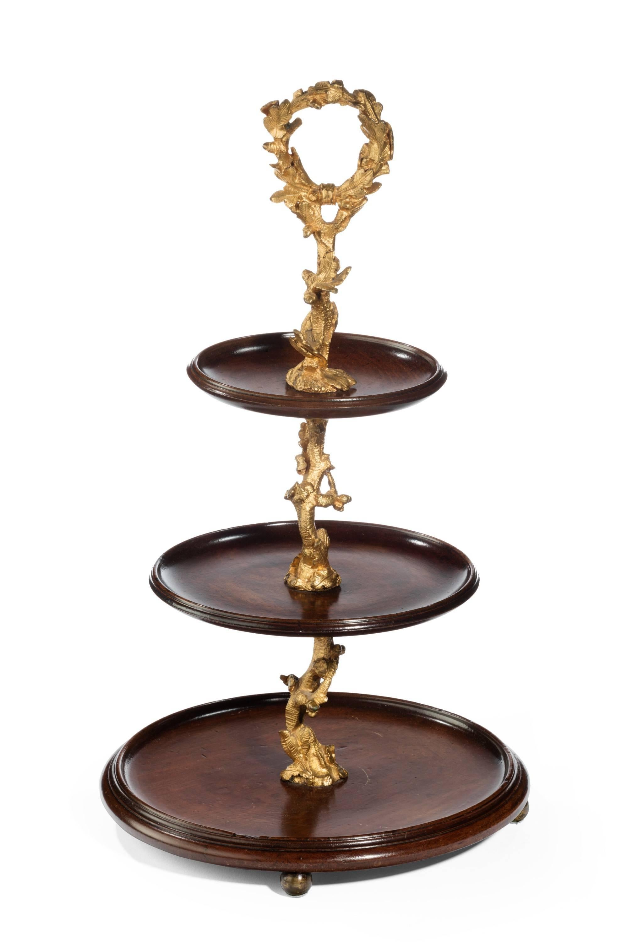 A most unusual late 19th century mahogany and gilt bronze three-tier table top stand raised on ball feet. The gilt bronze in wonderful original state. The mahogany well patinated.