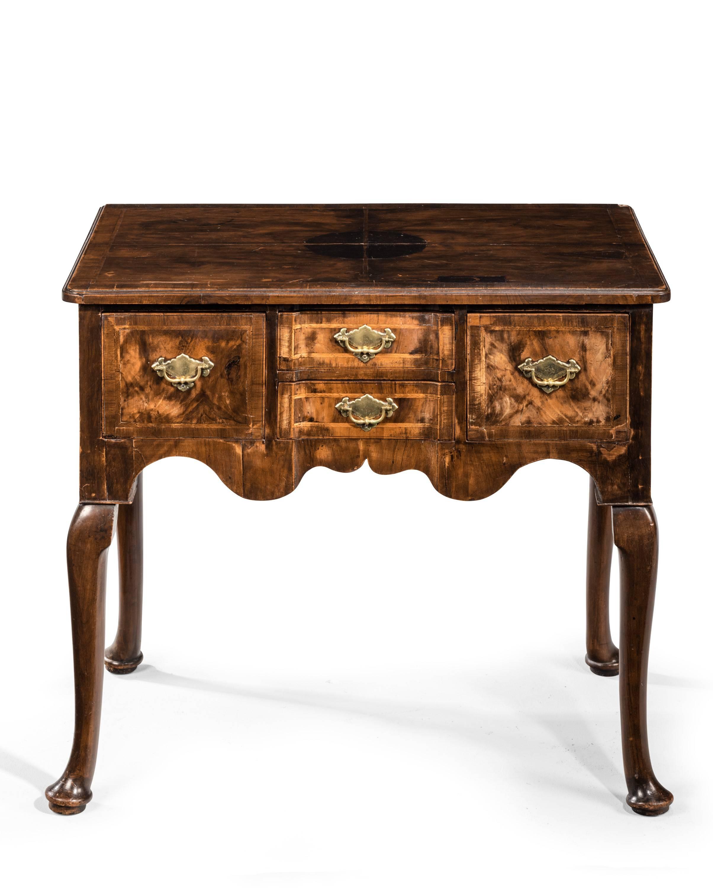 A mid-18th century walnut lowboy. With unusual concave section the two central tops. Quartered top with some restorations, broadly cross banded. Well shaped cabriole supports.