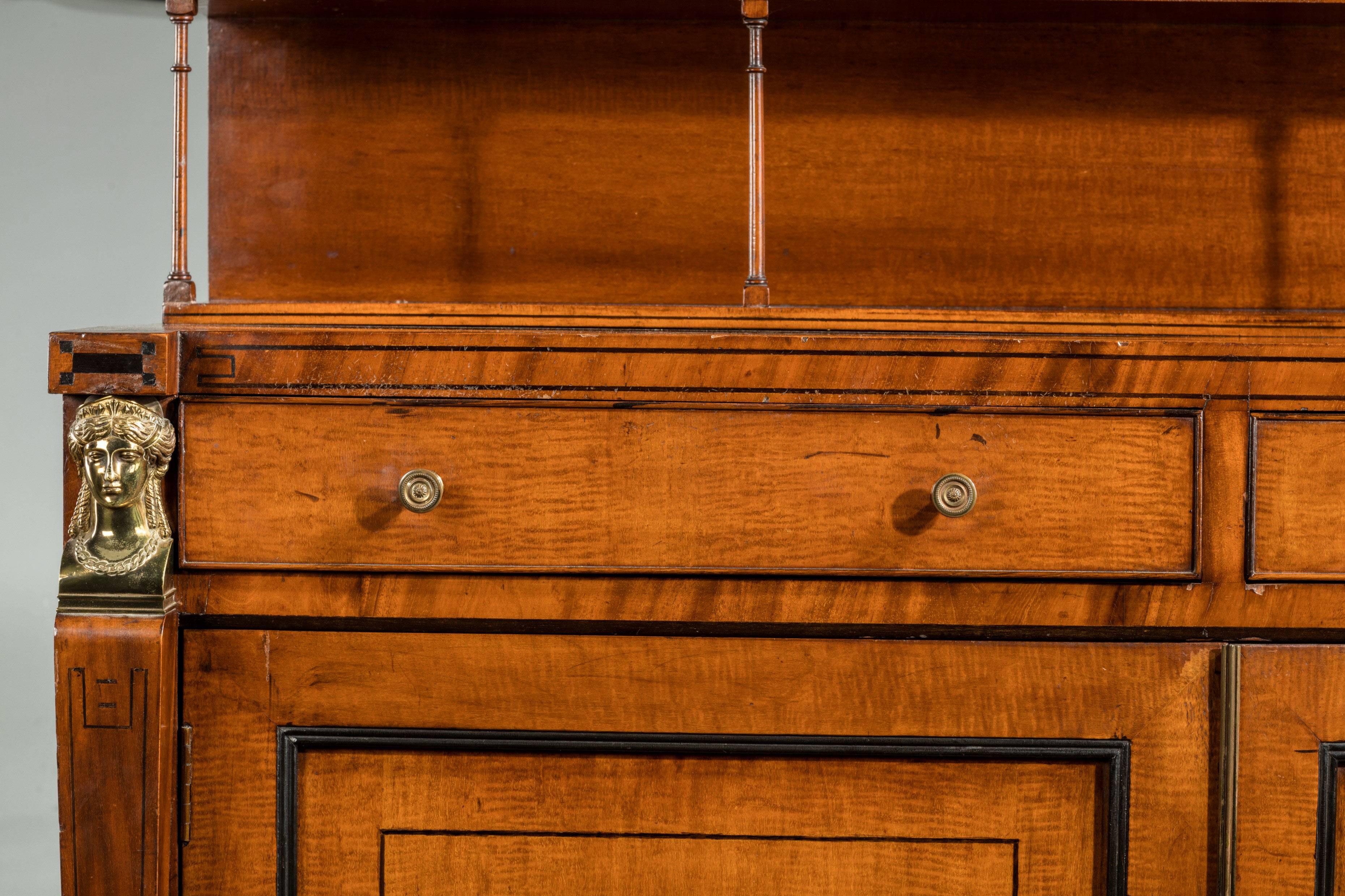 A very good quality Regency period mahogany chiffonier. Upper shelf supported by the fine quality turnings. Retaining the original gilt bronze gallery. The supports with sphinx’s head and feet. Fine line ebony inlay.