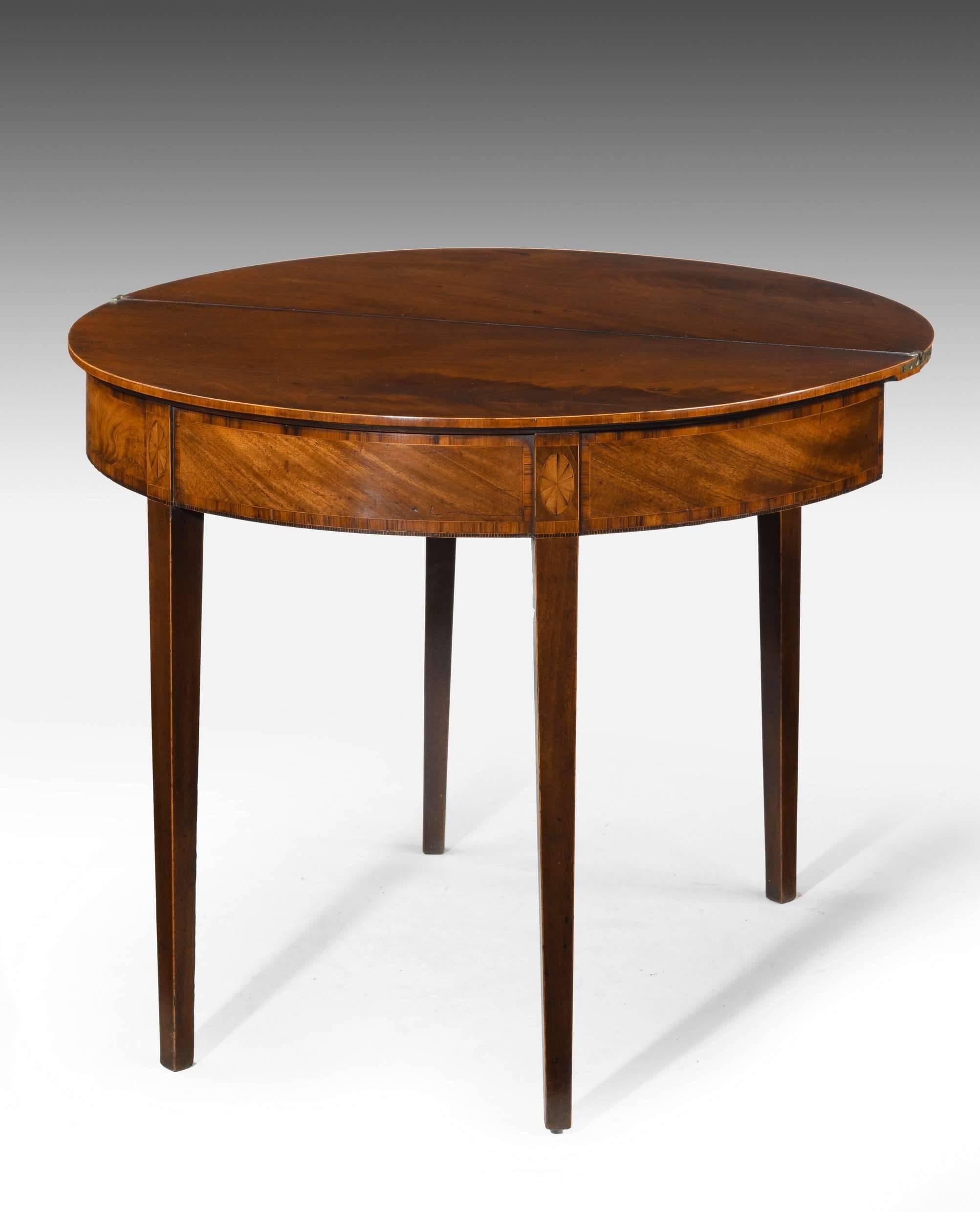 A good Sheraton period mahogany demilune tea table. The tapering supports with boxwood edging. The top sections with oval inlaid patera. Beautifully figured timbers.

When closed 17.75 inches.