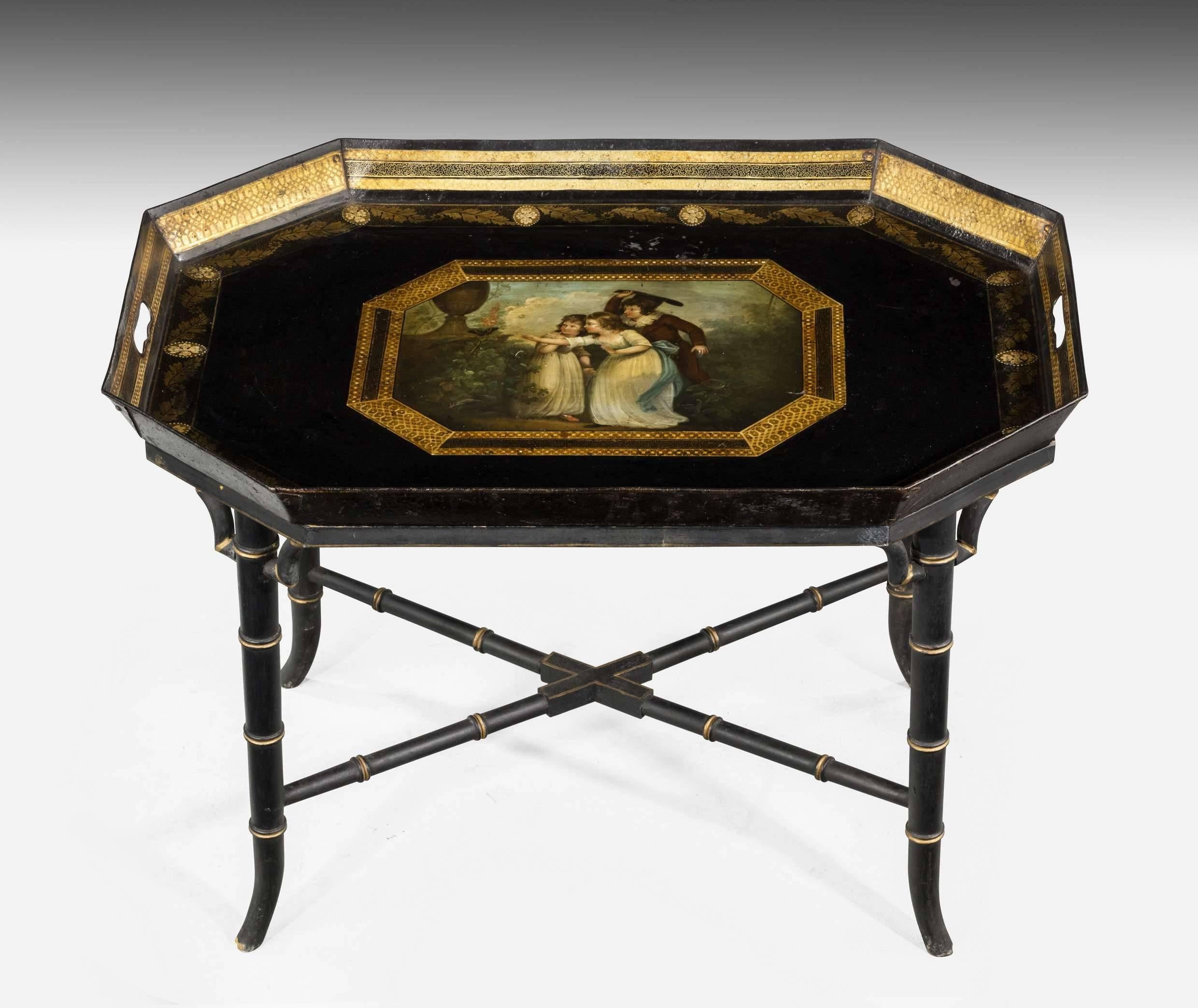 A beautifully painted polychrome tray signed Innocent mischief. On a custom built 20th century Stand. Octagonal shaped with finely decorated leaf and reserve gilded border. The central painting of a youth and two young girls in elegant dresses