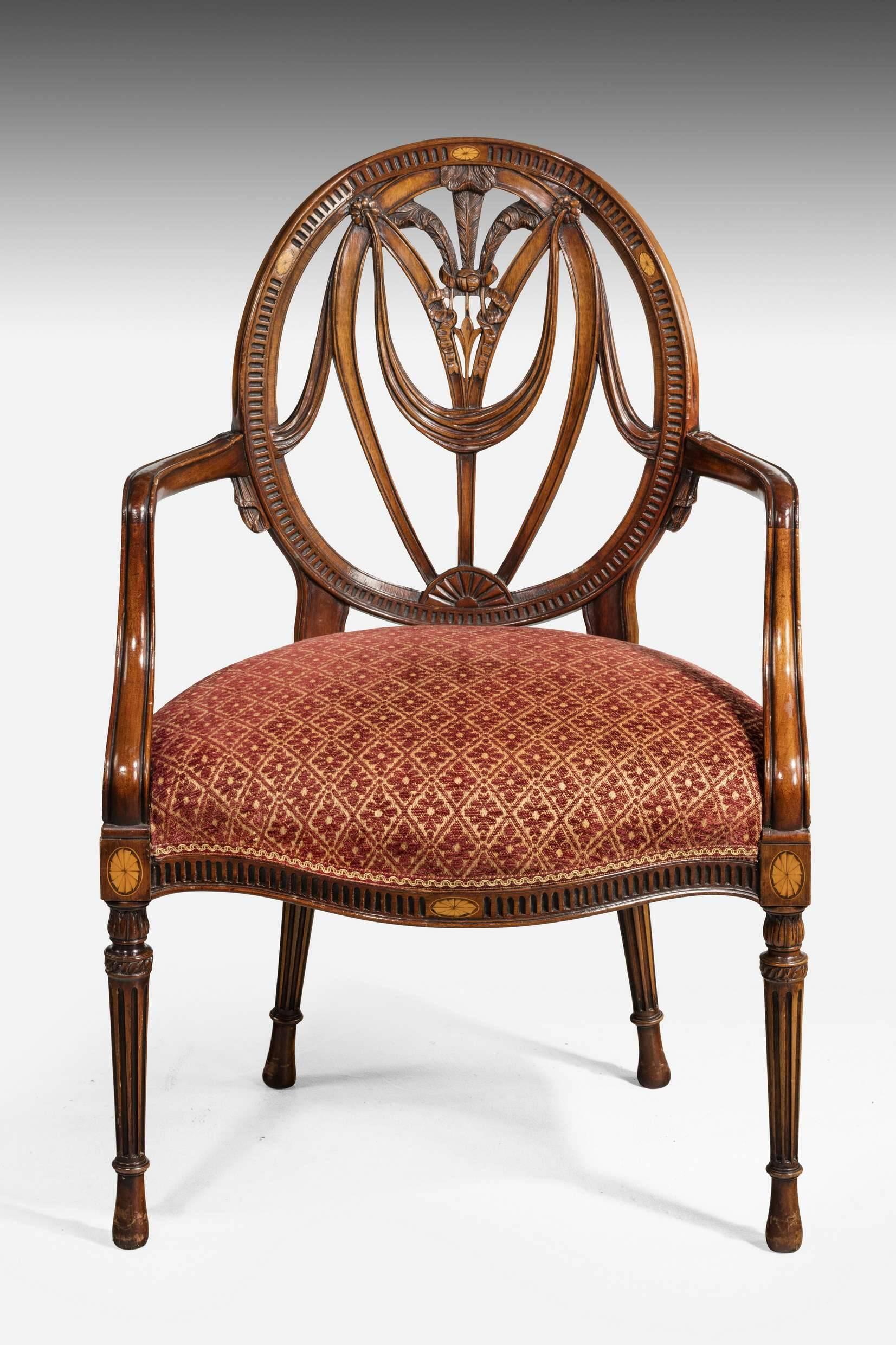 A quite exceptional set of ten mid-20th century mahogany framed elbow chairs. The oval backs concave with a huge amount of carving. Oval fan inlaid patera to the top of the shields and the supports. Arcaded carving to the outer shield toning exactly