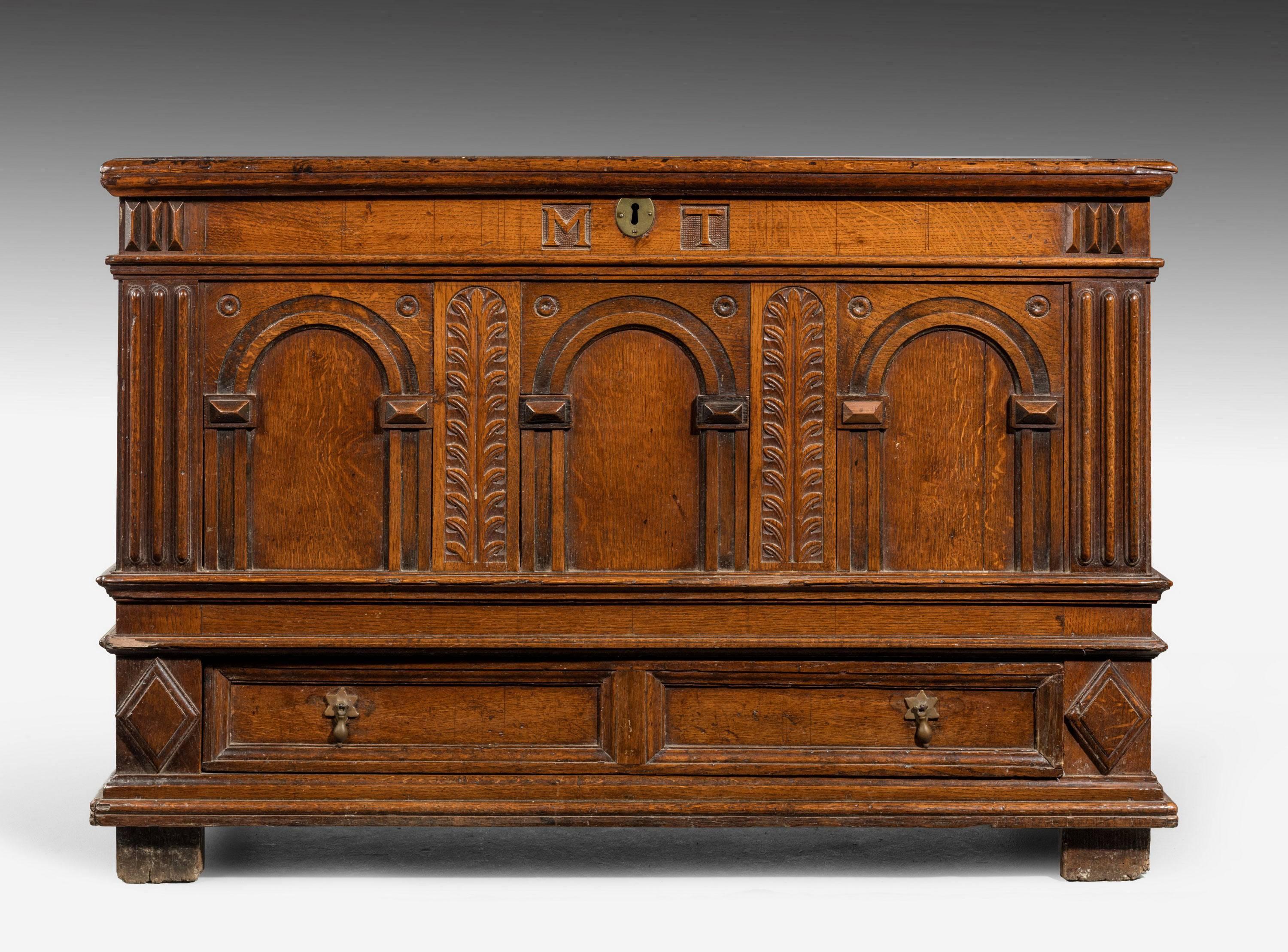 A good early 18th century figured oak kist. The base incorporating two drawers. Carved arcadic decoration with round handles to the front and well panelled ends.