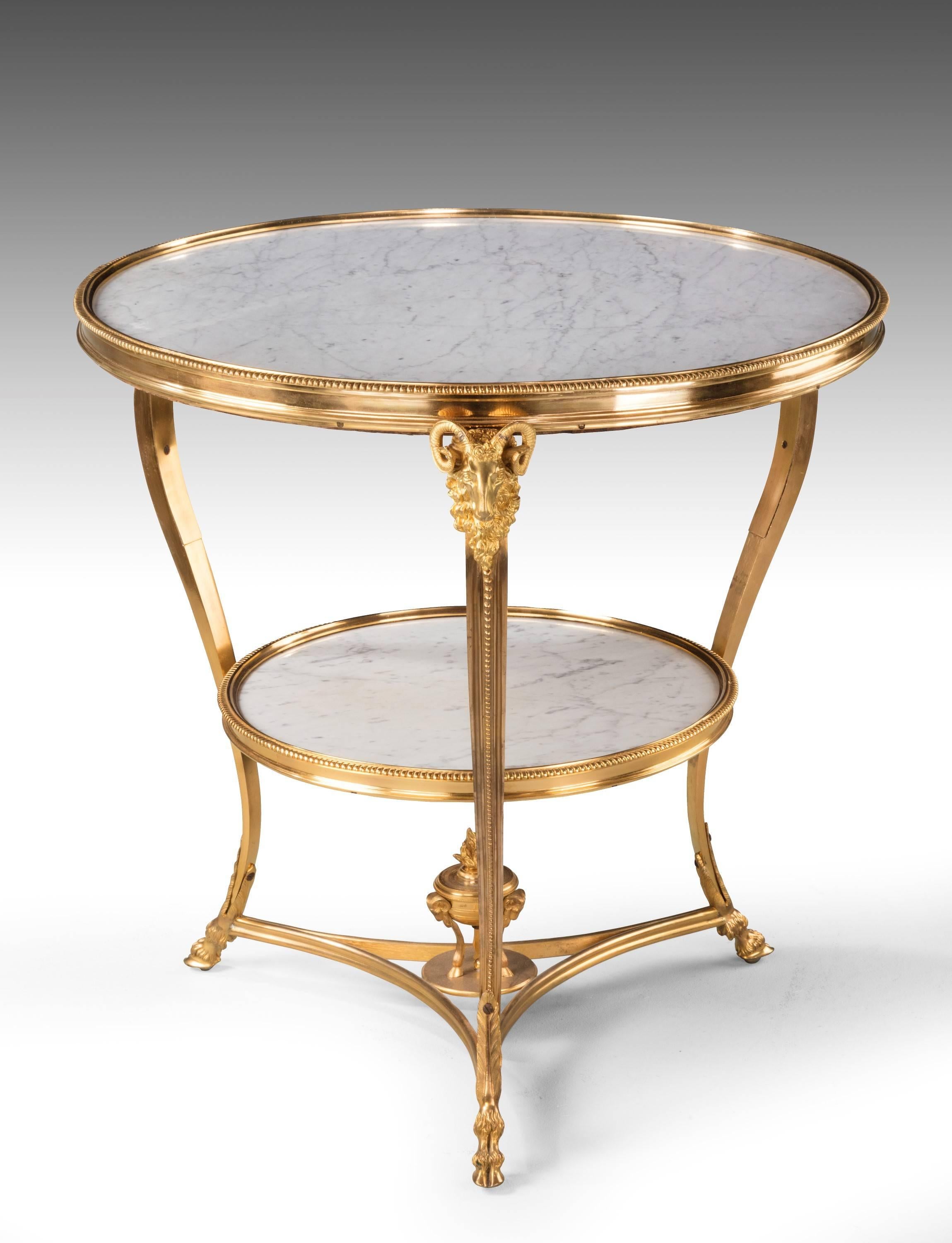 Fine quality French two-tier gueridon in gilt bronze retaining the original gilding. The two centre sections retaining the original finely veined grey and white marble top. The supports with beautifully cast ram’s heads. 

Excellent overall