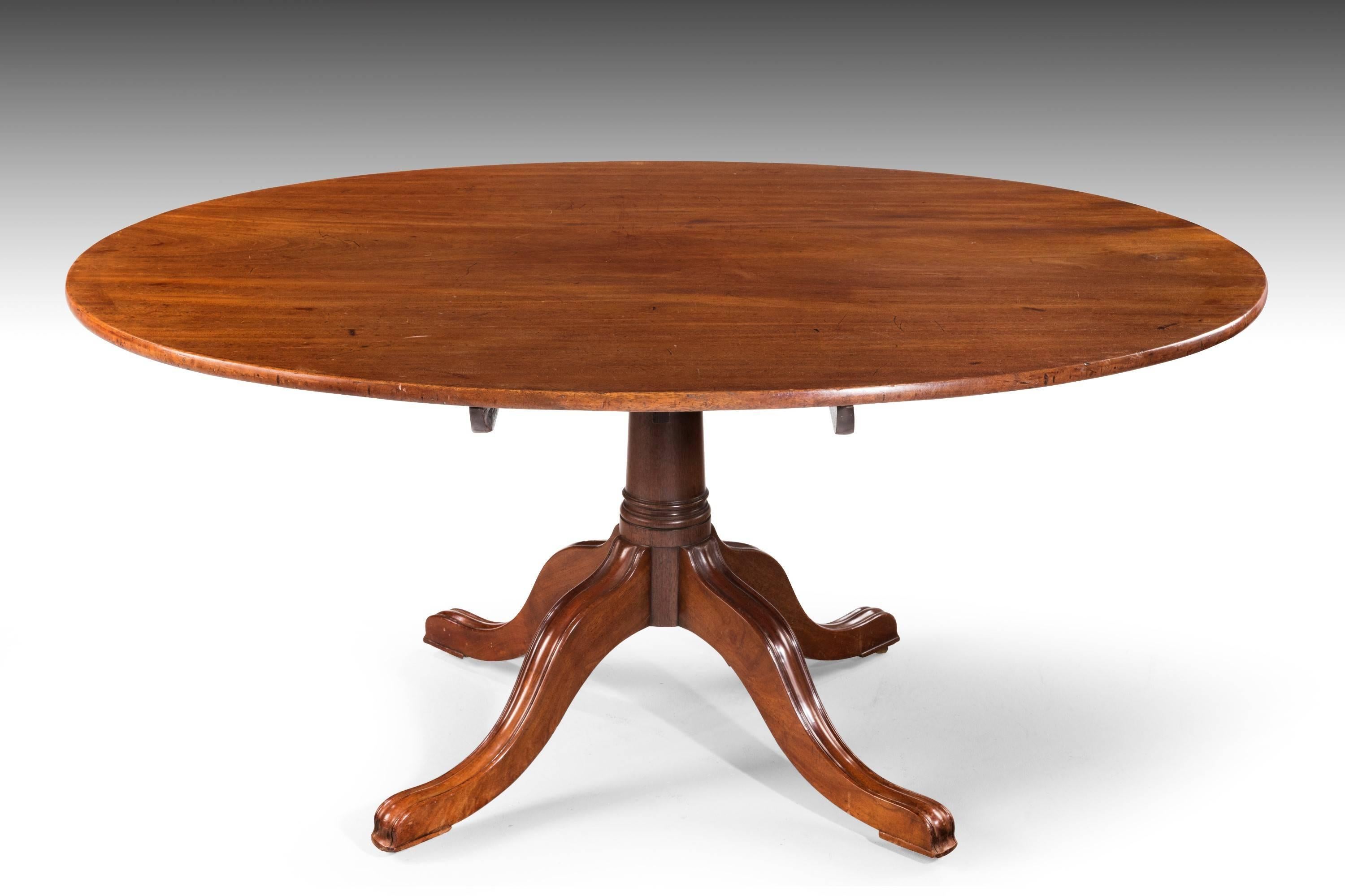 A fine George III period oval mahogany dining table with a single piece beautifully figured top. Over a barrel support terminating in four reeded spread legs. Exceptional quality.
