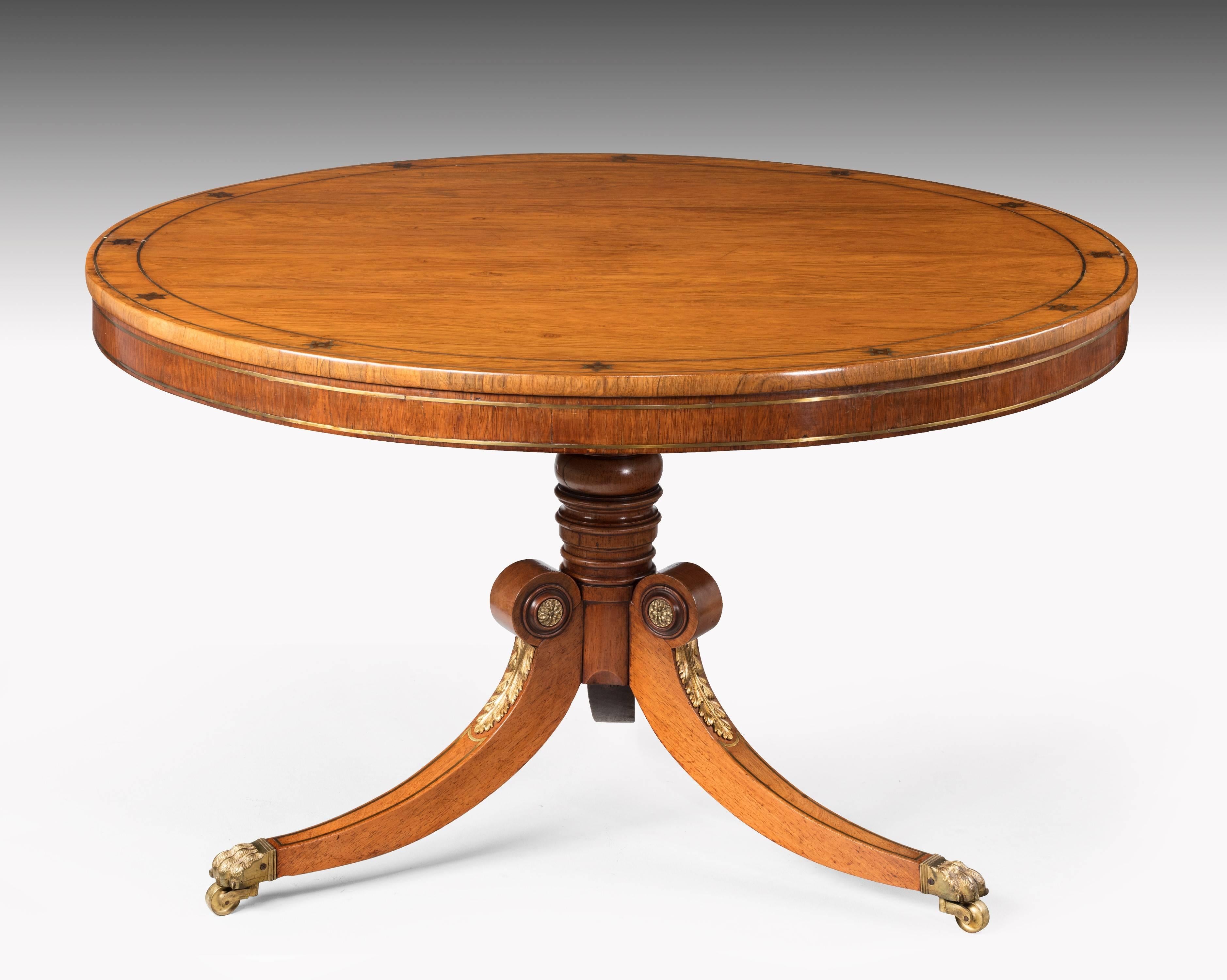 A very good quality Regency period circular table. The outer rim with a double brass inlay incorporating stylized stars. The base with swept supports and finely cast acanthus leaves.