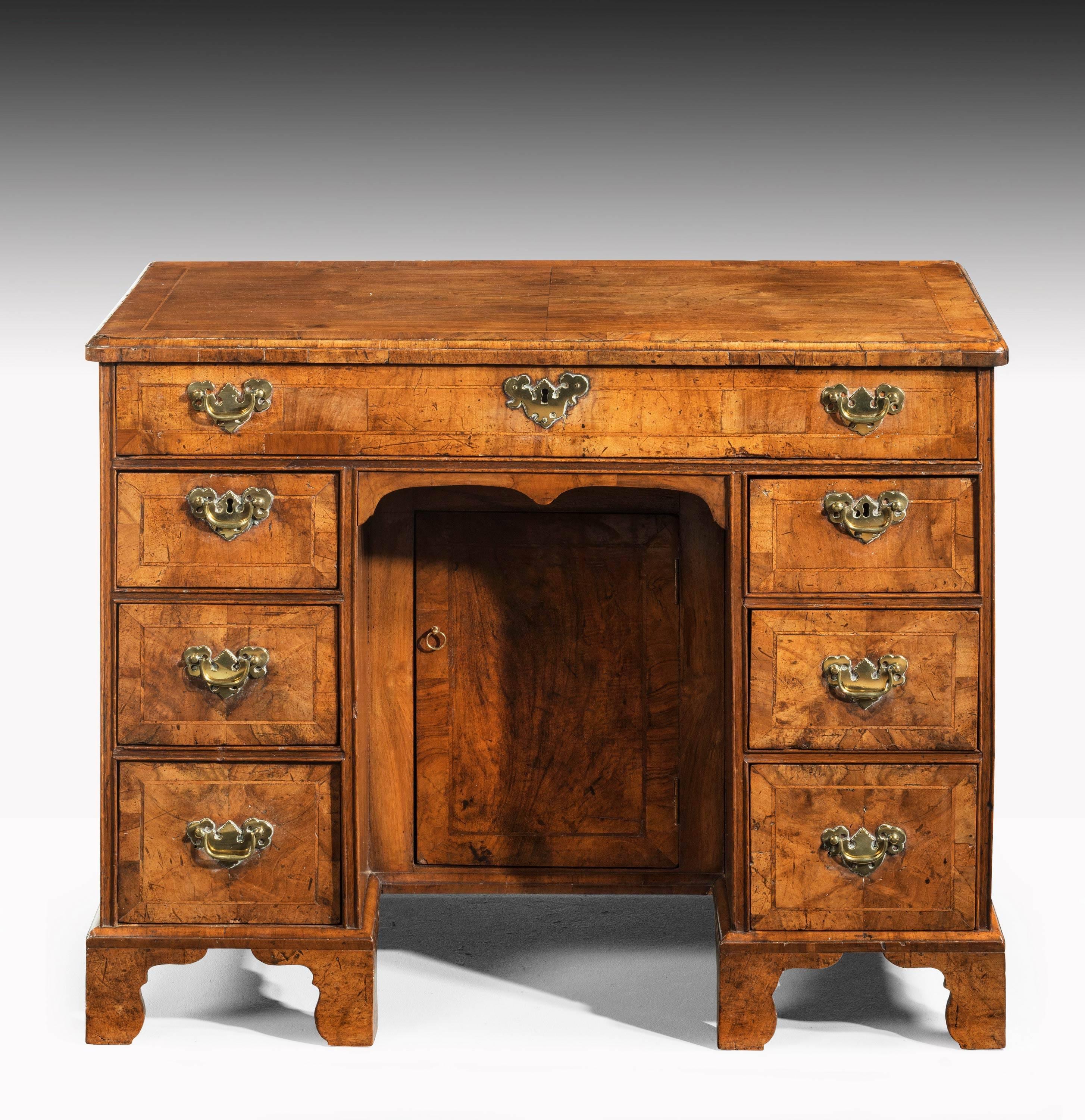 A handsome mid-18th century walnut kneehole desk with very good details. The drawers all crossbanded with edge line inlay. The top broadly crossbanded outside a quartered panel. Excellent overall color and patina. Replaced brass.

 