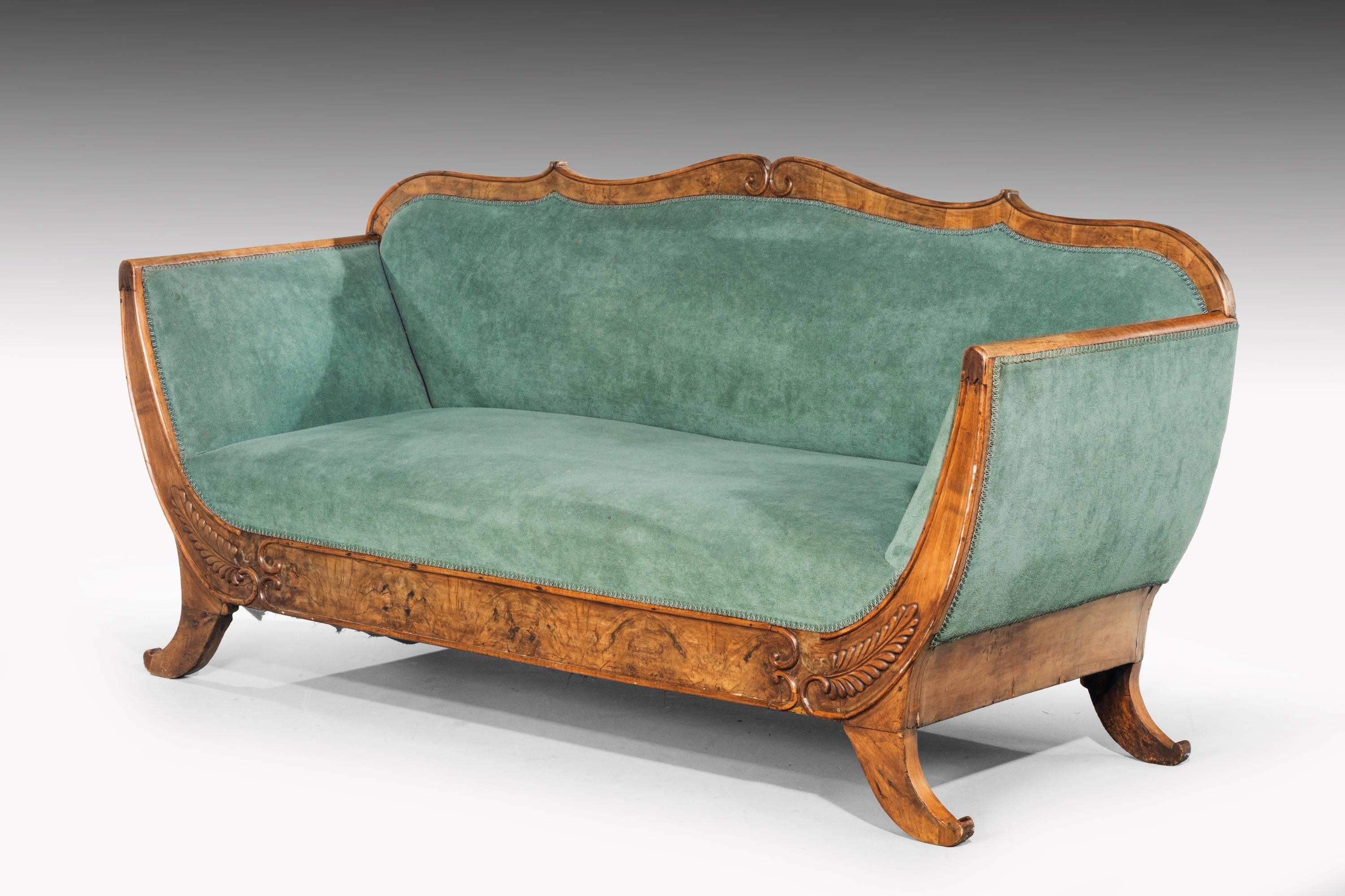A very good quality Regency period walnut sofa. The timbers particularly well figured, on swept sabre supports with extended leaf carving above. 

    