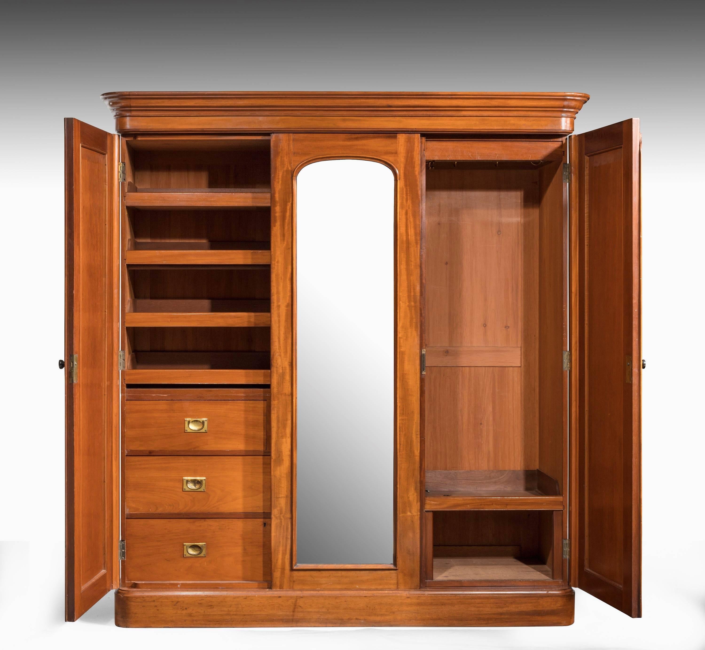 A well figured mid-19th century mahogany wardrobe. The central section with a full-length mirror. The interior very finely fitted with drawers and linen trays.