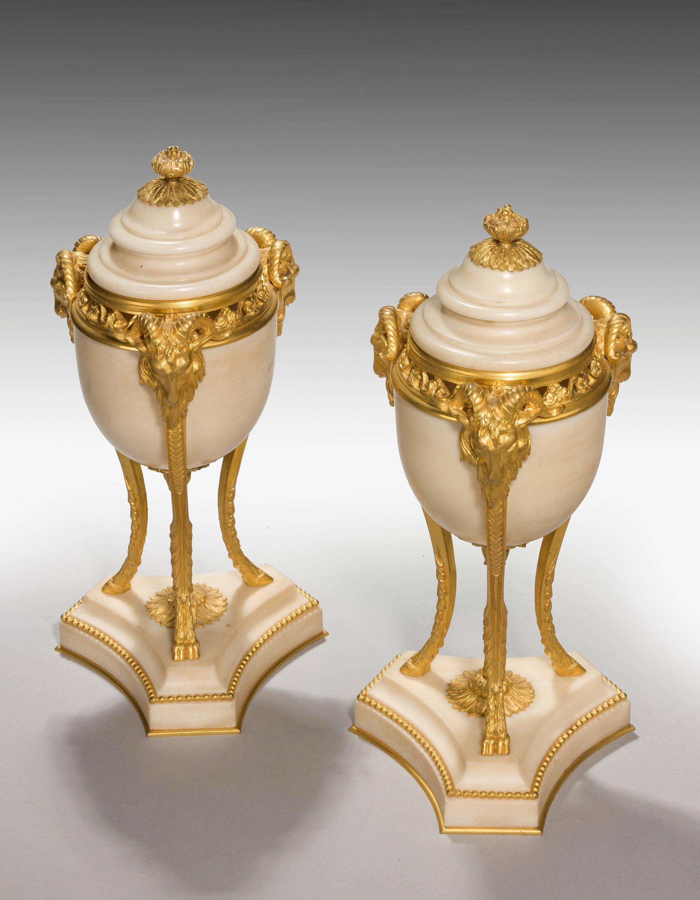 An elegant pair of early 20th century French gilt bronze and marble-lidded vases, the triple support with goats-head mounts. With concave triform bases with bead and floral decoration. Original gilding.