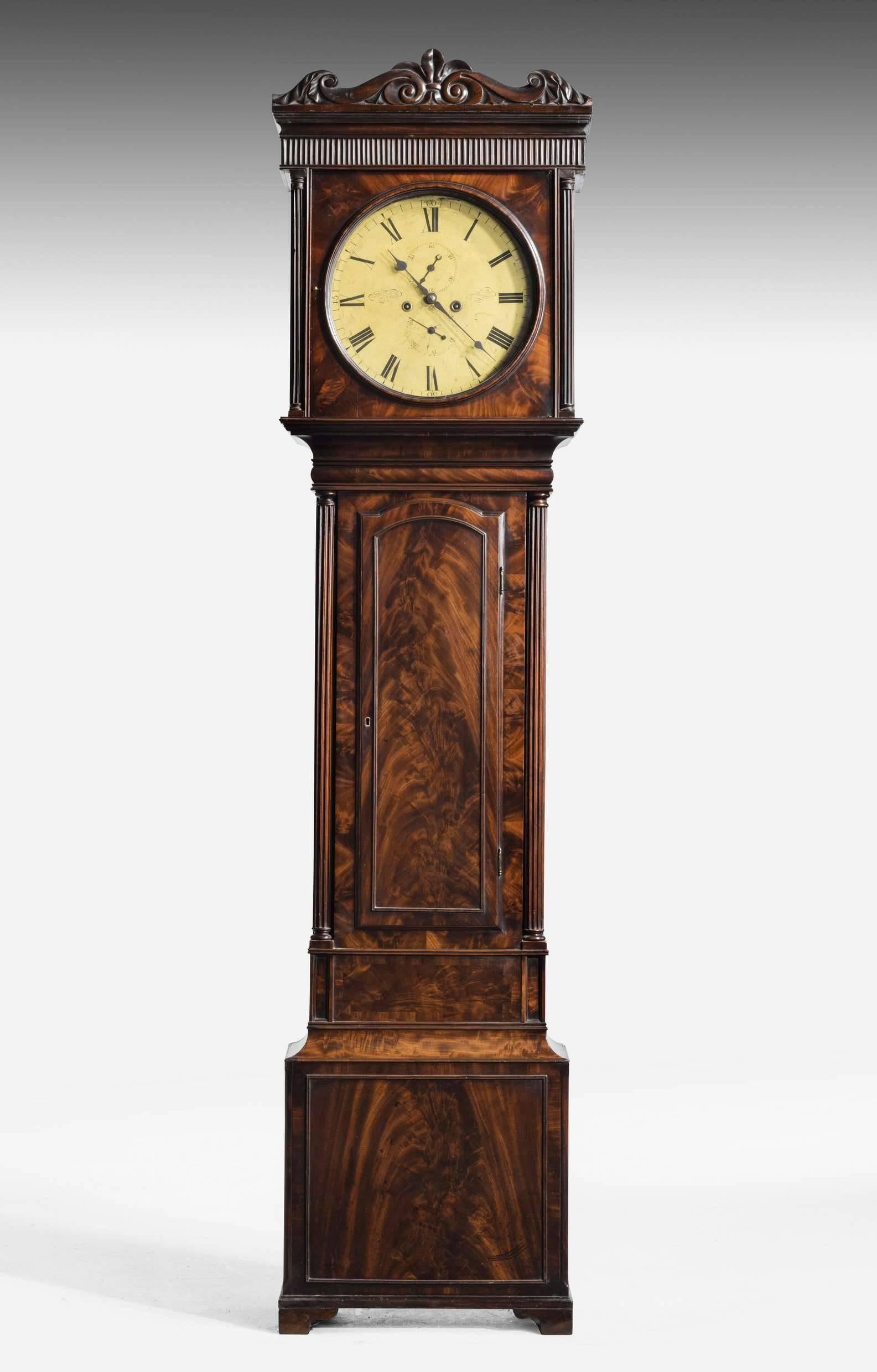 An early 19th century mahogany longcase clock by Alexander Ralston. The eight-day bell striking movement with anchor escapement, the 14 inch painted circular Roman numeral dial carved with subsidiary seconds and date dials and signed Alexander