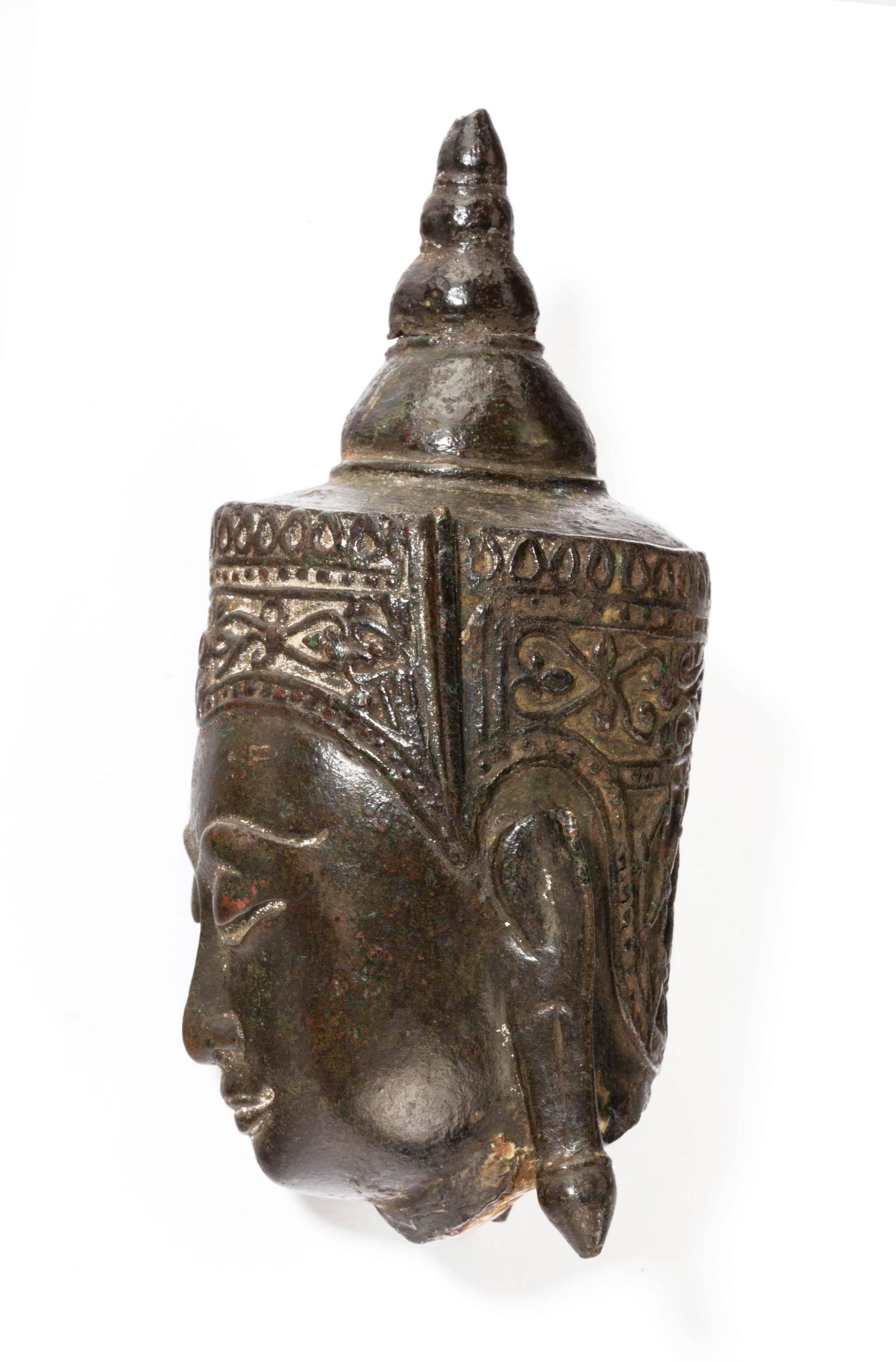 An Indian bronze figure head of a deity from a larger figure. Excellent even patination.