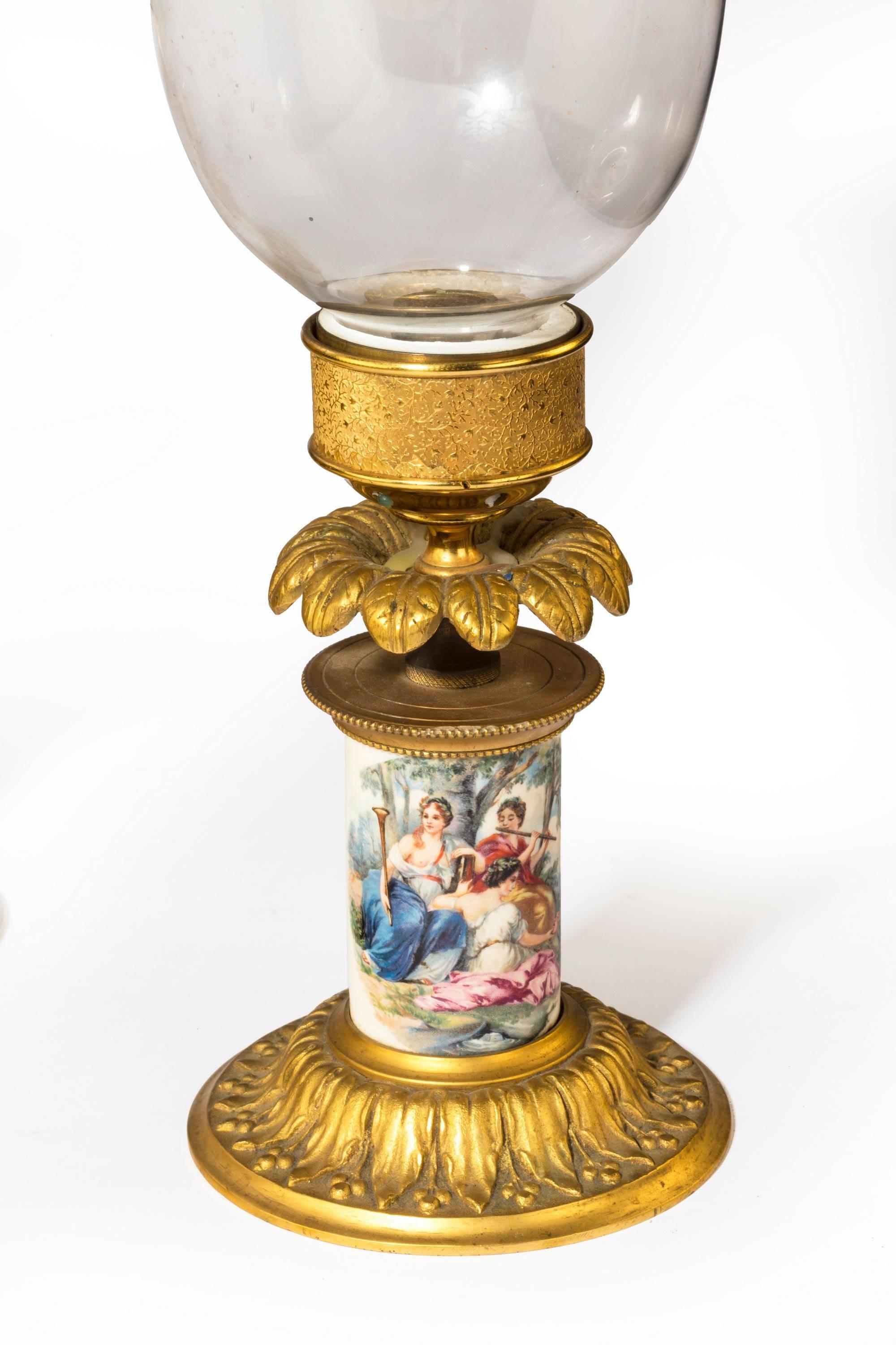 A pair of gilt bronze porcelain and glass storm lanterns. Retaining the original etched shades. The porcelain centre column with scenes influenced by Voltaire.