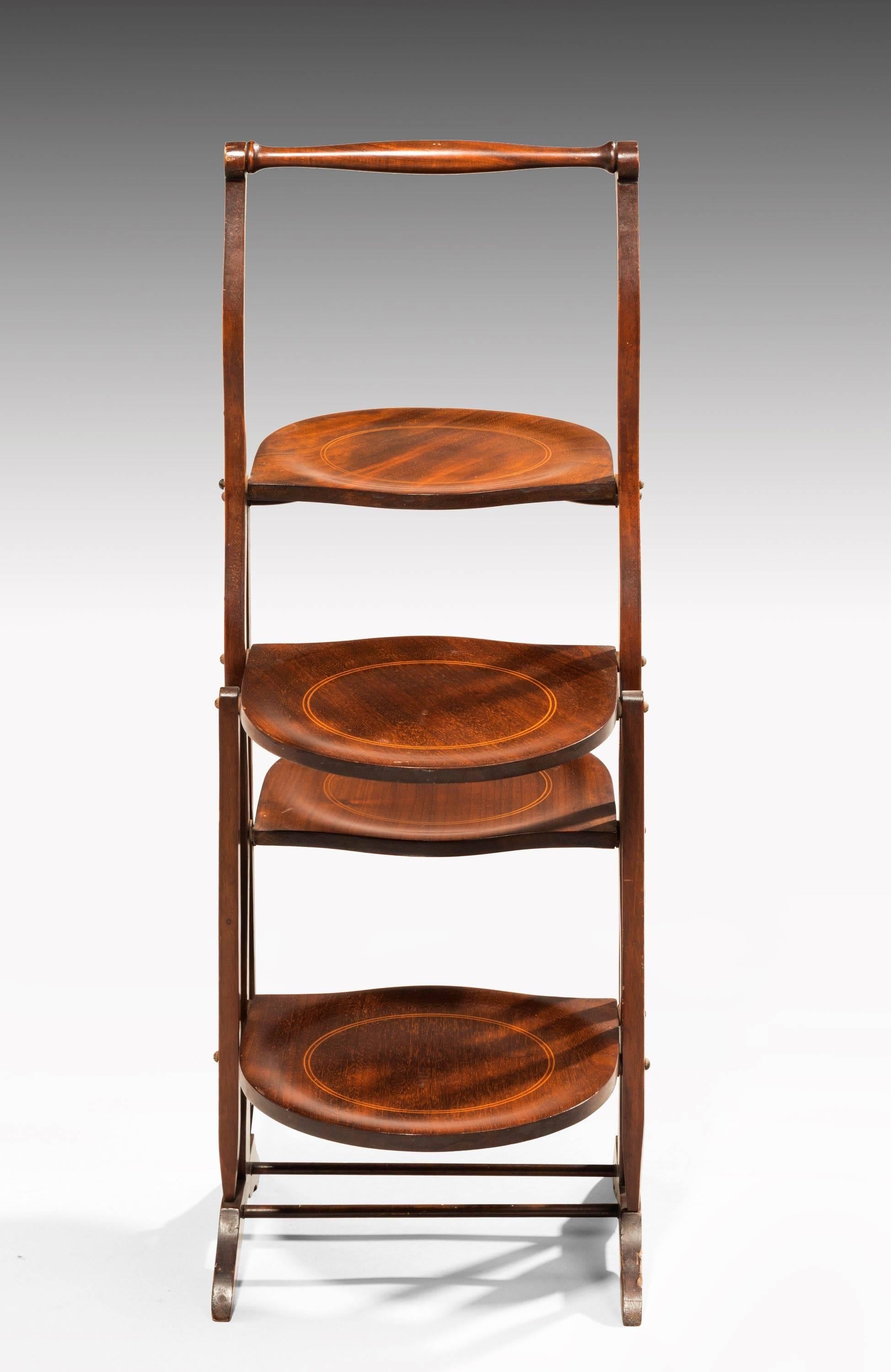 A pretty Edwardian two-sided mahogany folding cake stand. Circular boxwood inlay to all shaped trays.