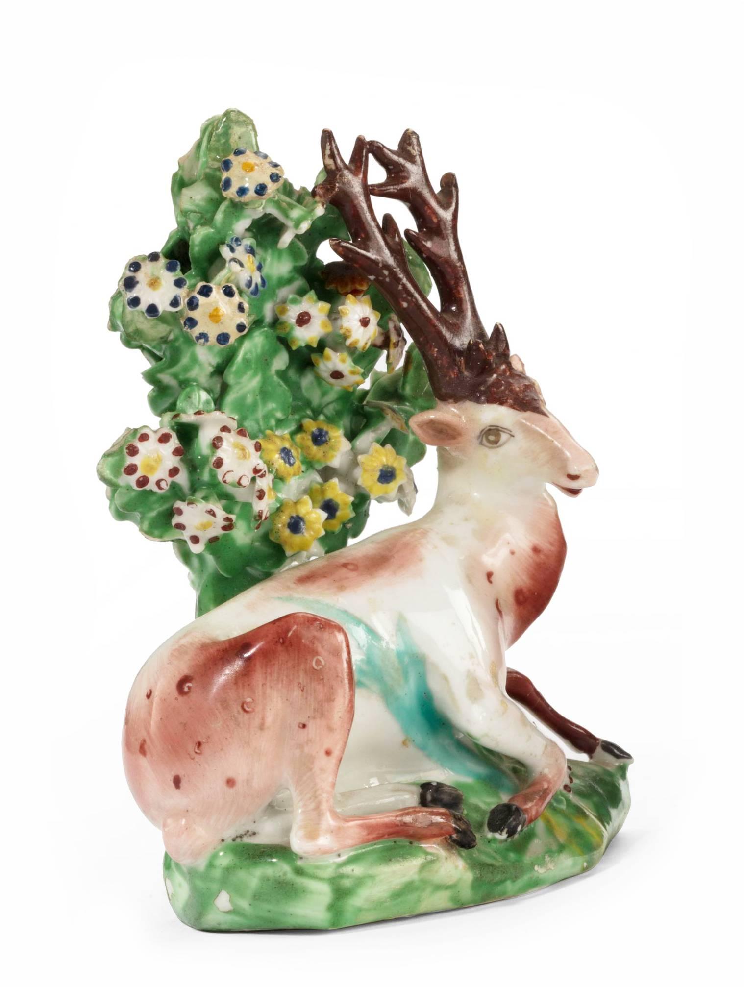 An attractive Staffordshire pottery model of a recumbent stag with bocage decoration.