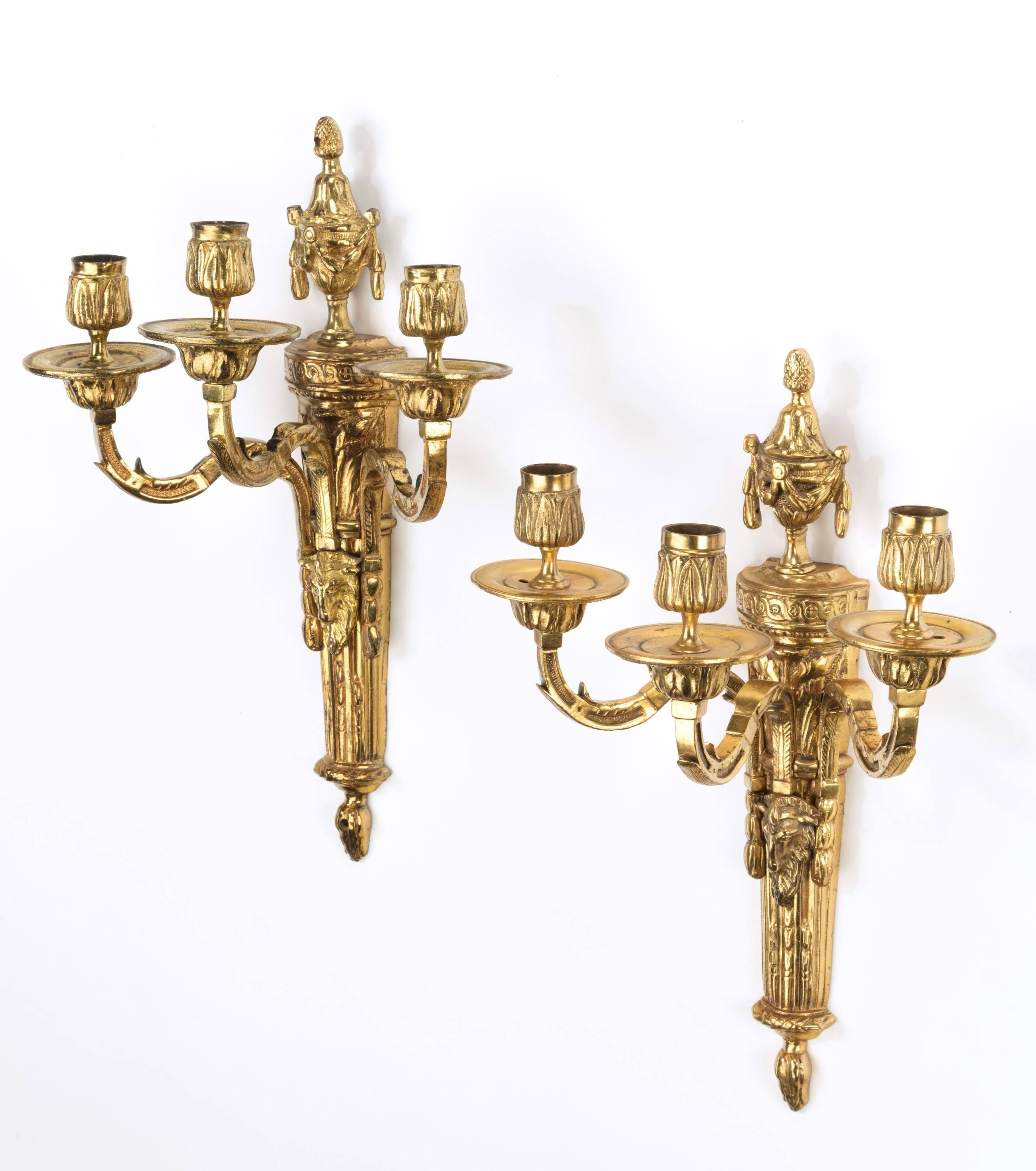A pair of gilt bronze three-arm wall lights with original gilding.