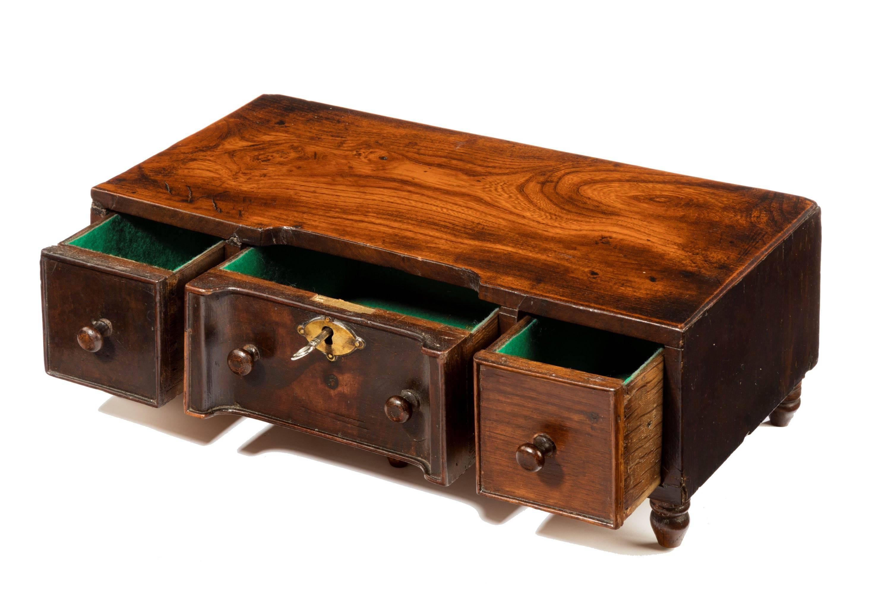 An unusual George III period elm miniature table chest. The concave central section with three drawers. Very well figured and patinated top.