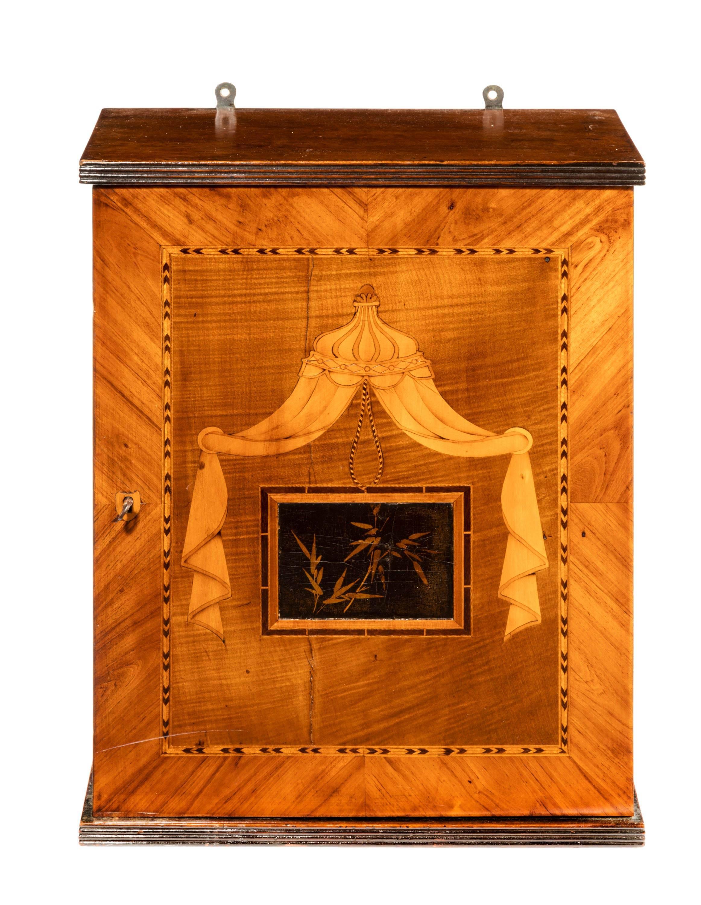 An exotic, small, wall hanging cabinet in finely cut timbers of olive, walnut, Satinwood and ebony.