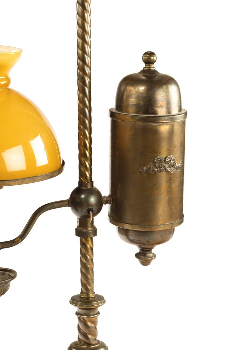 A quite rare Argand table oil lamp. English or French. Scrolling openwork cast finial above a rope-twist shaft, the cylindrical reservoir and lamp arm height adjustable on the stem, the burner beneath an amber glass shade, above a domed base on