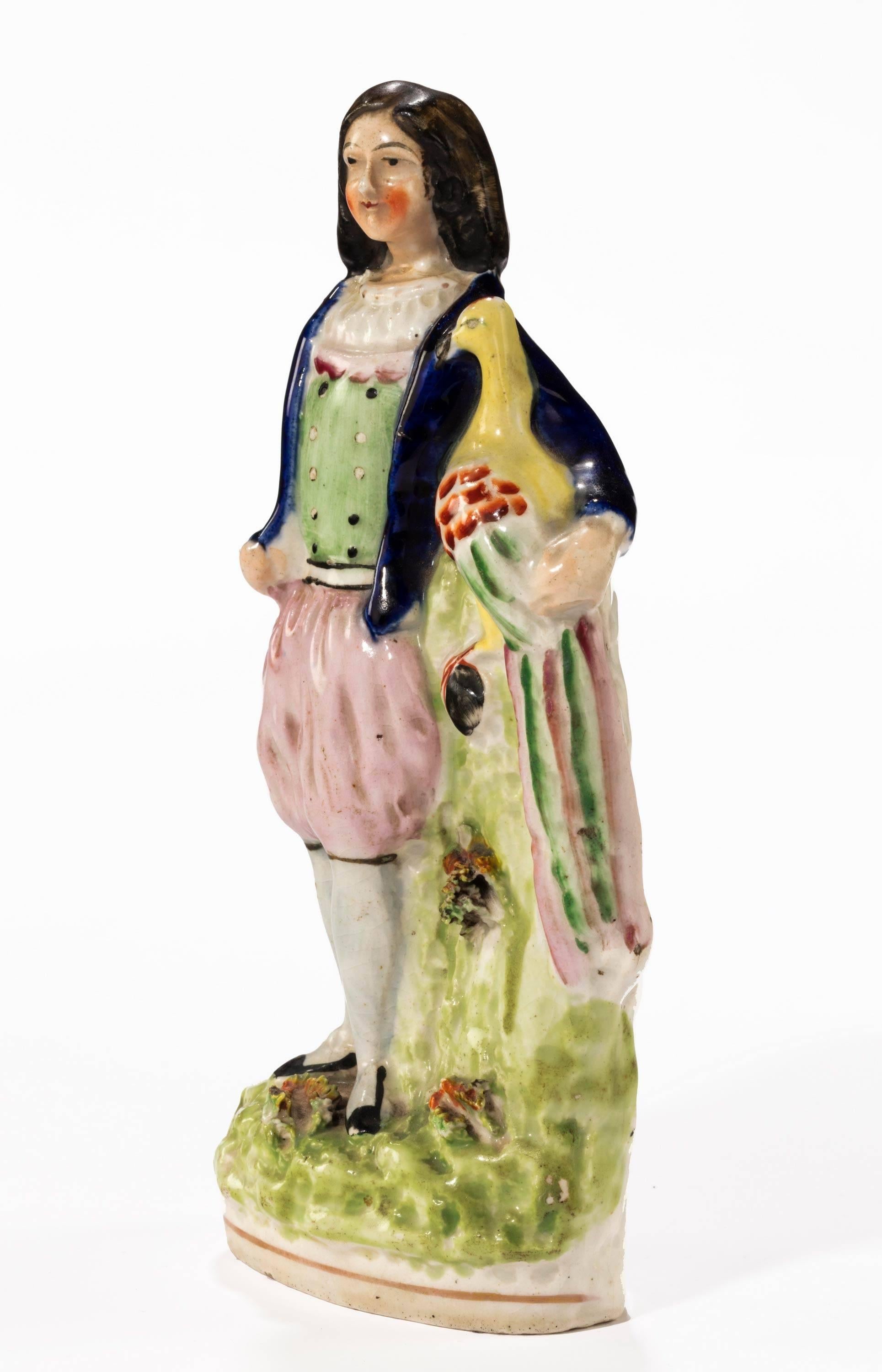 A Staffordshire figure of a young lady holding a peacock.