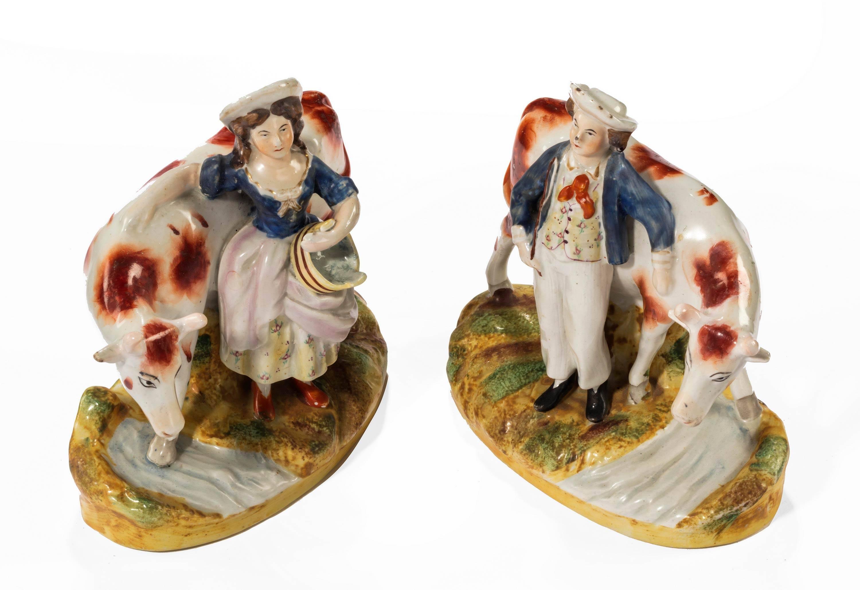 A pair of typical Staffordshire farm yard figures of a male and female with cows. Good overall condition with good enameling.