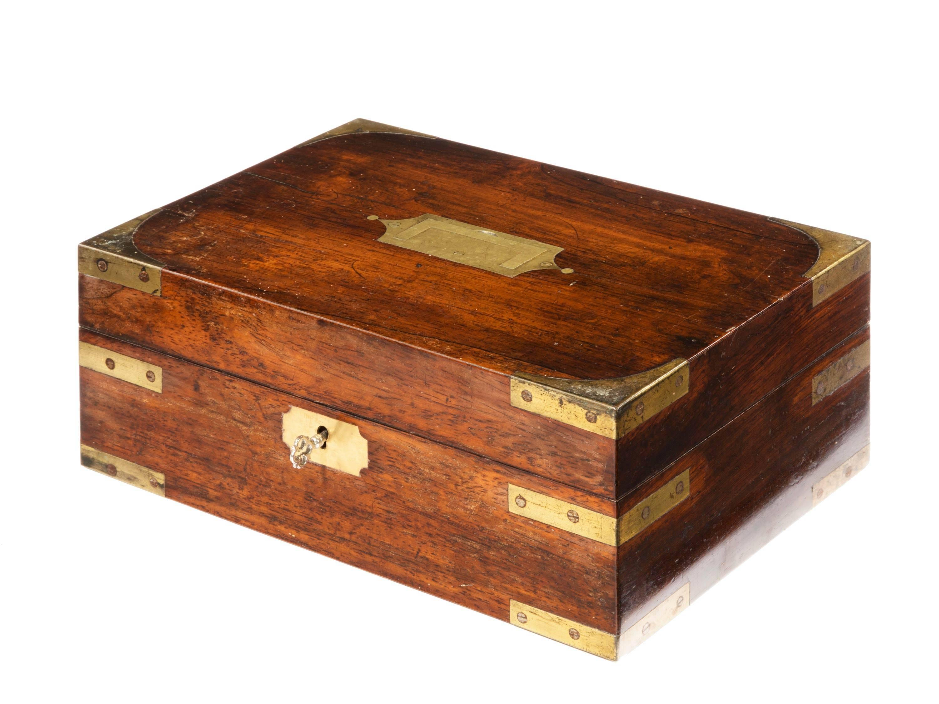 A good brass-mounted mahogany travelling box. Retaining all original inset brass corners and panels. The interior fitted with small well gilded writing section. With a pen section and boxes.