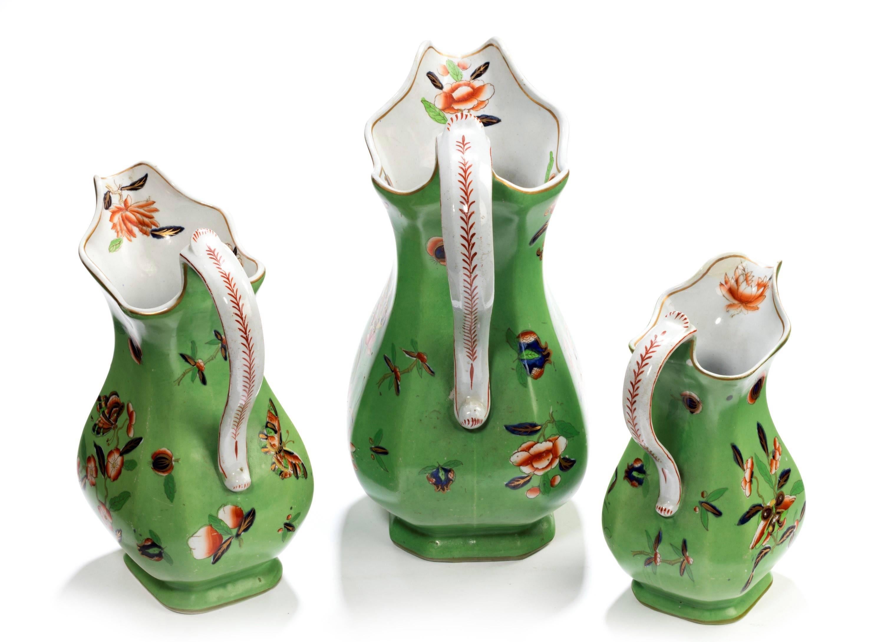 A particularly good set of three graduated Staffordshire jugs. With solid green background decorated with fans, foliage and oriental flowers. 

The medium sized -

Height 8 inches
Width 6 inches 
Depth 3.5 inches

The smallest -

Height 7