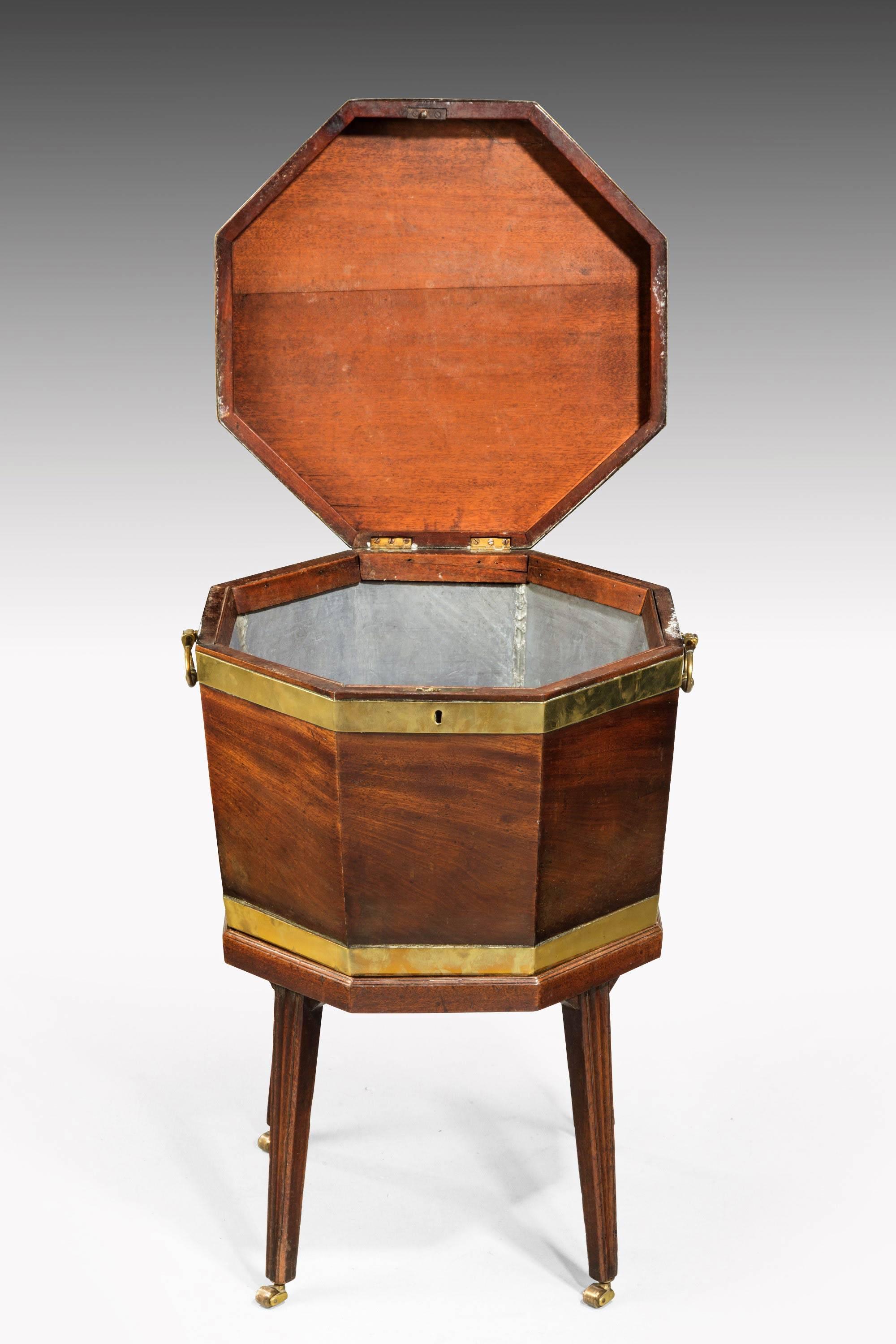 A George III period mahogany octagonal wine cooler. On finely tapering supports. Retaining original shoes and castors. Brass bound upper section. The interior with a replaced zinc liner.