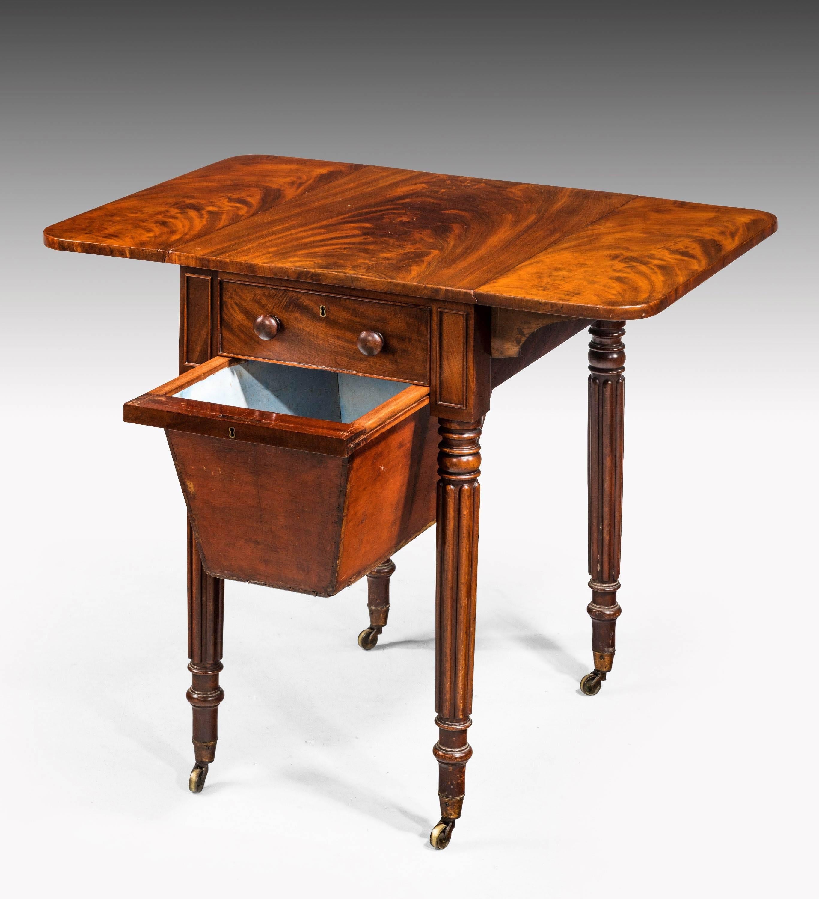 Late Regency period mahogany Pembroke work table. The beautifully figured timbers matching left and right hand to the top sections. A suspended sewing basket to the lower section between the well turned and reeded supports. Original shoes and