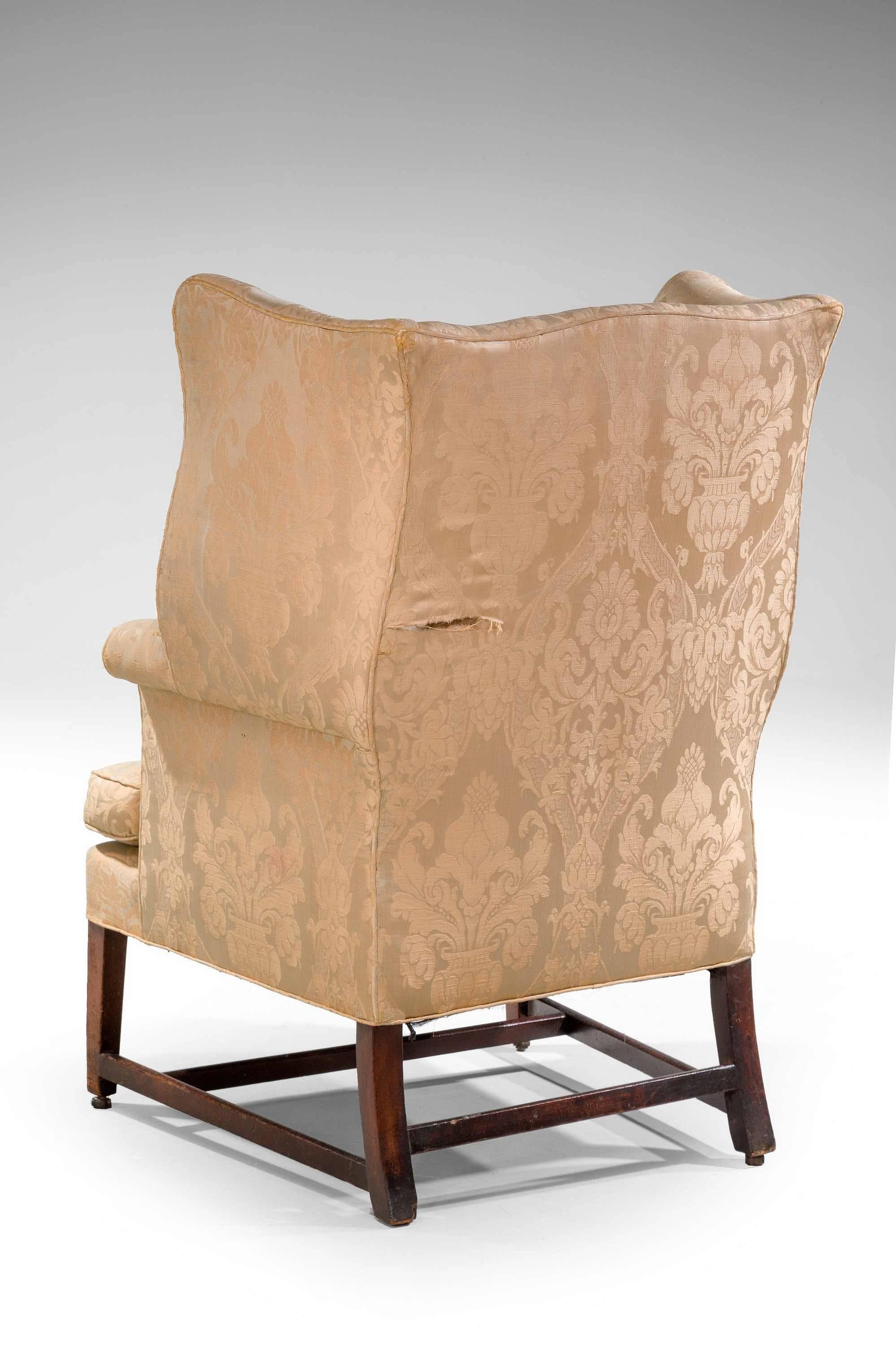A good George III Chippendale period mahogany wing chair with very well shaped serpentine wings, square tapering supports joined by crossed stretchers. 

