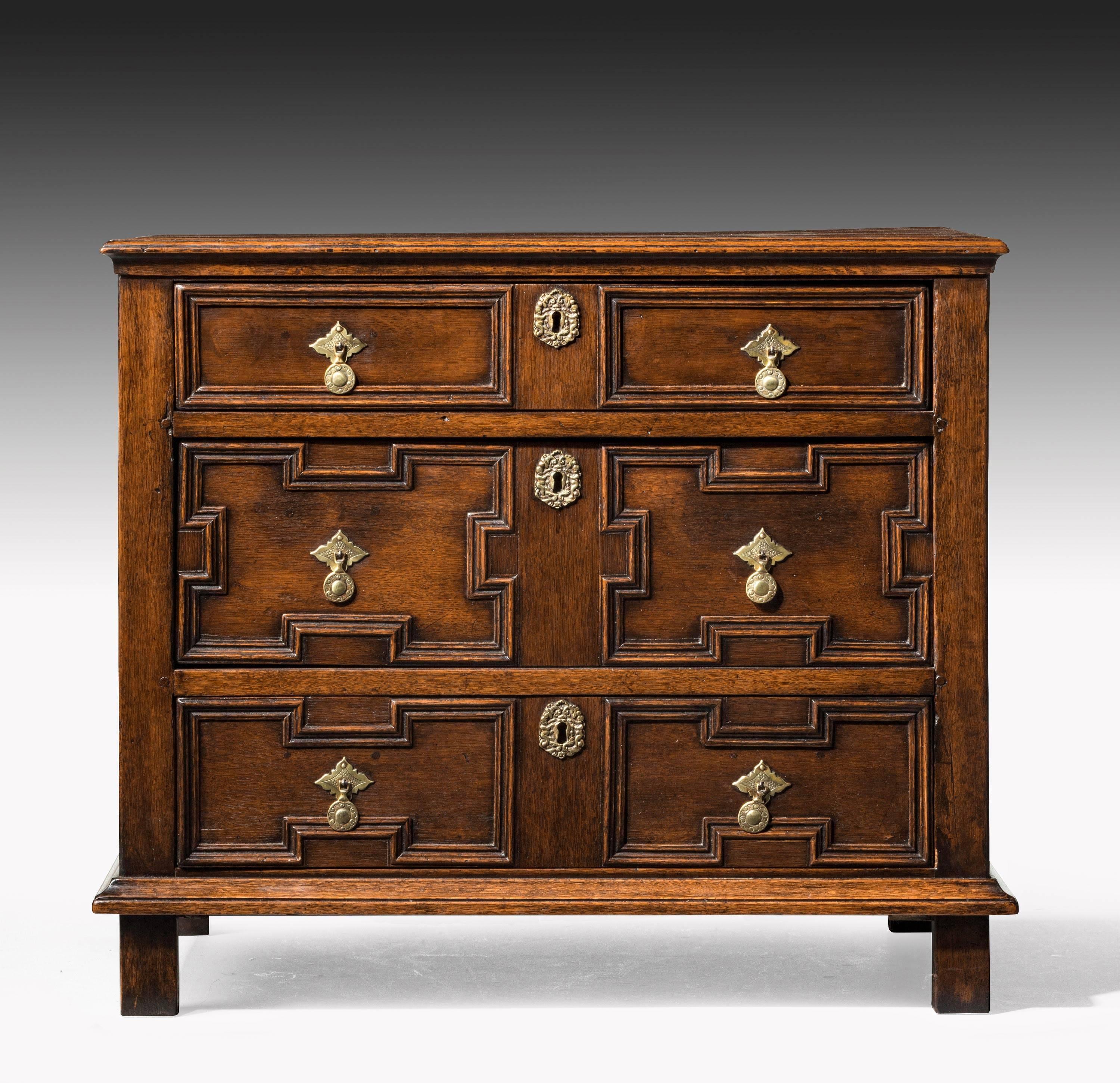 A good small late 17th century chest of drawers with geometrically shaped fronts to the drawers and unusually four-panel sections to the ends. On original square feet.