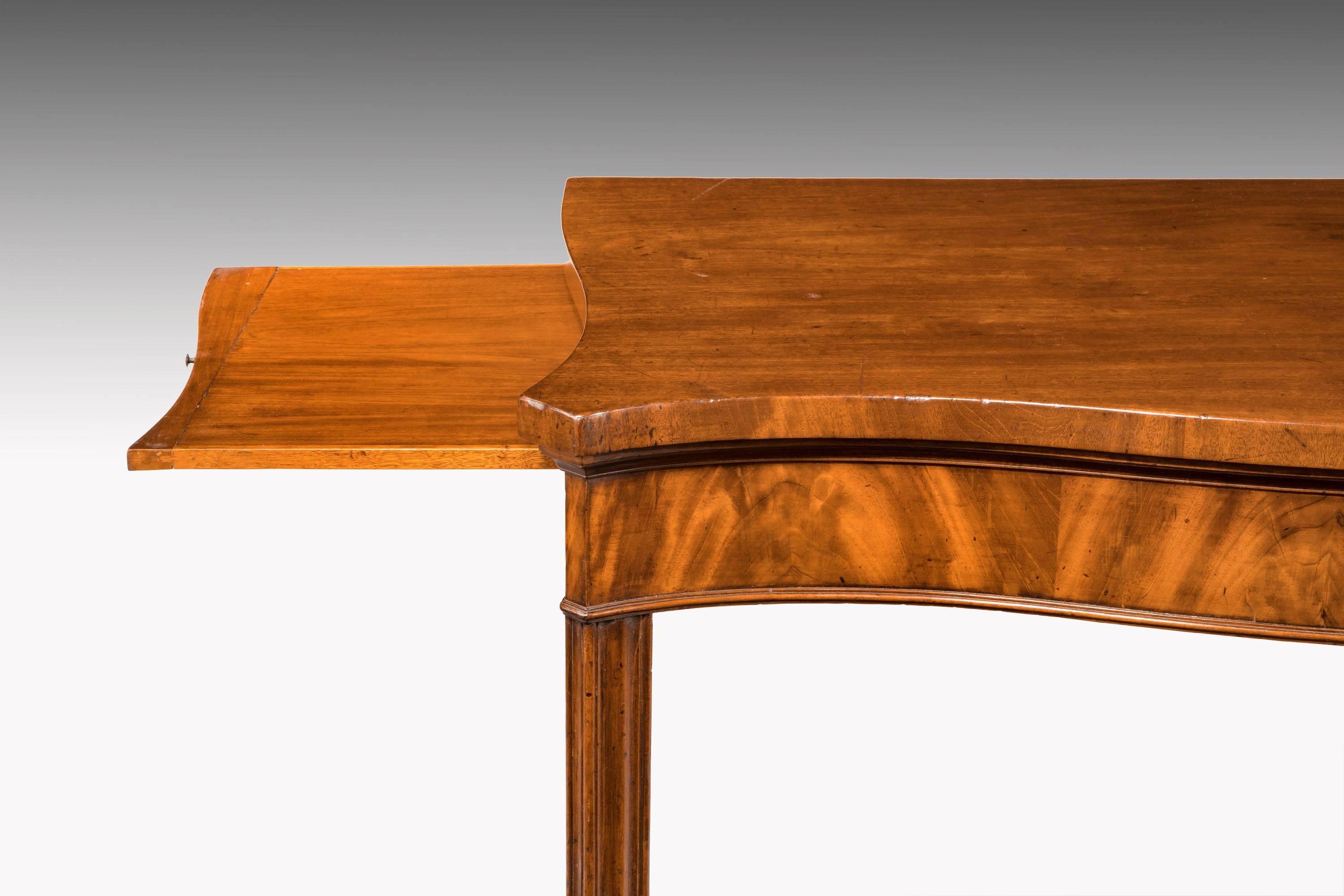A fine George III period mahogany serpentine serving table with the unusual benefit of two slides, one to each side extending its potential usefulness. Beautifully figured timbers to the front frieze. On chamfered square supports. 

The slides 17
