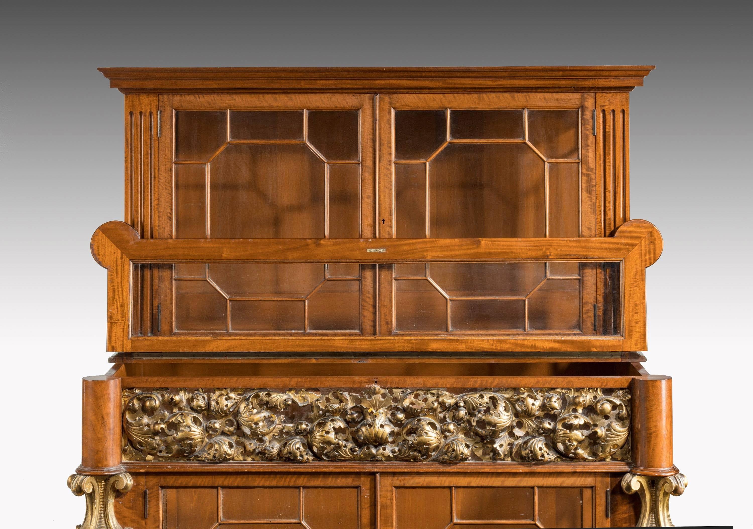 A most unusual mid-19th century satinwood cabinet. With finely carved and elaborate giltwood decoration. The two sections glazed including the ends.