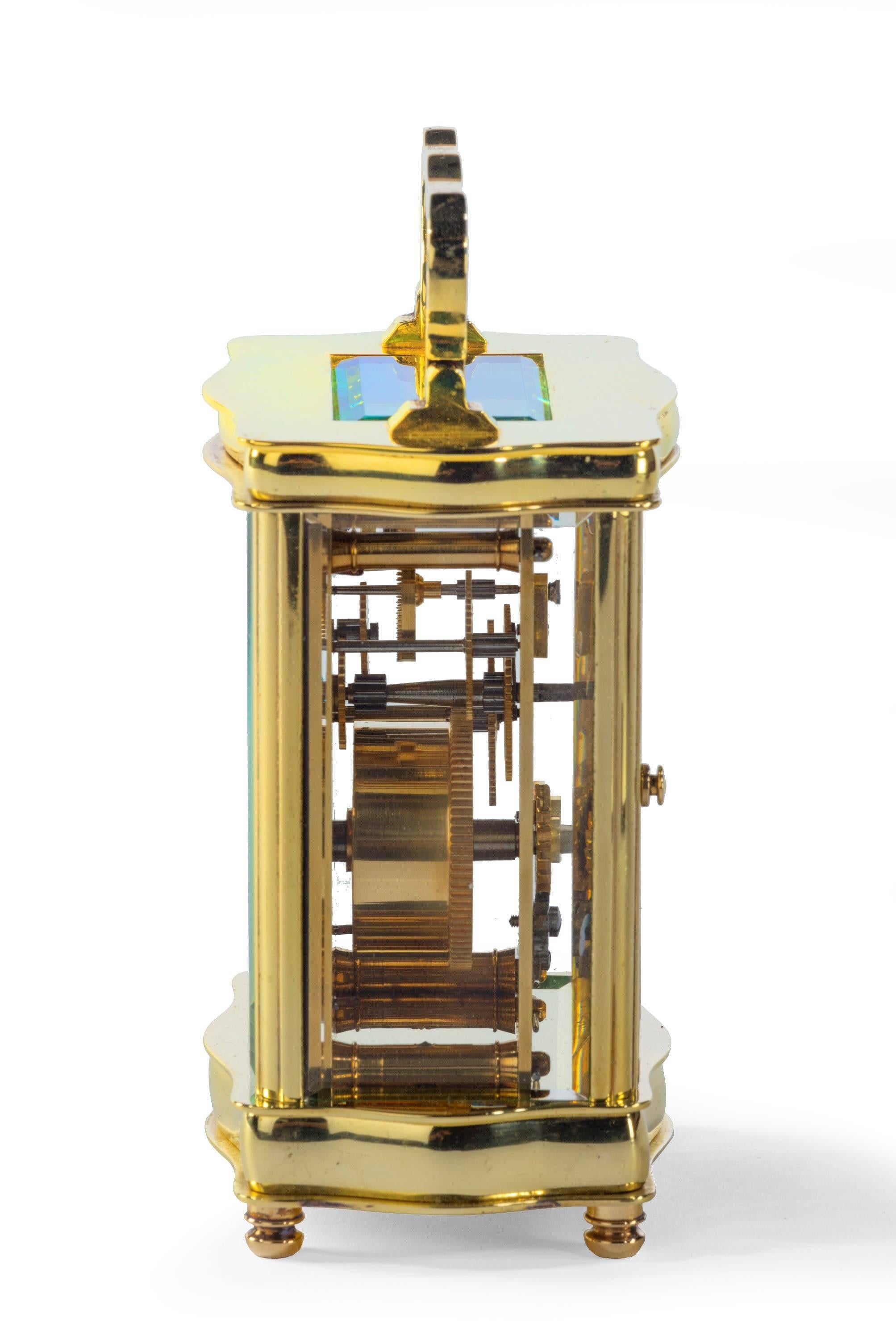 A brass carriage timepiece, unsigned, 20th century, of serpentine outline, the French eight-day movement with platform cylinder escapement and white enamel Roman numeral dial, the case with bevel glass panels, 13 cm high excluding handle, in a